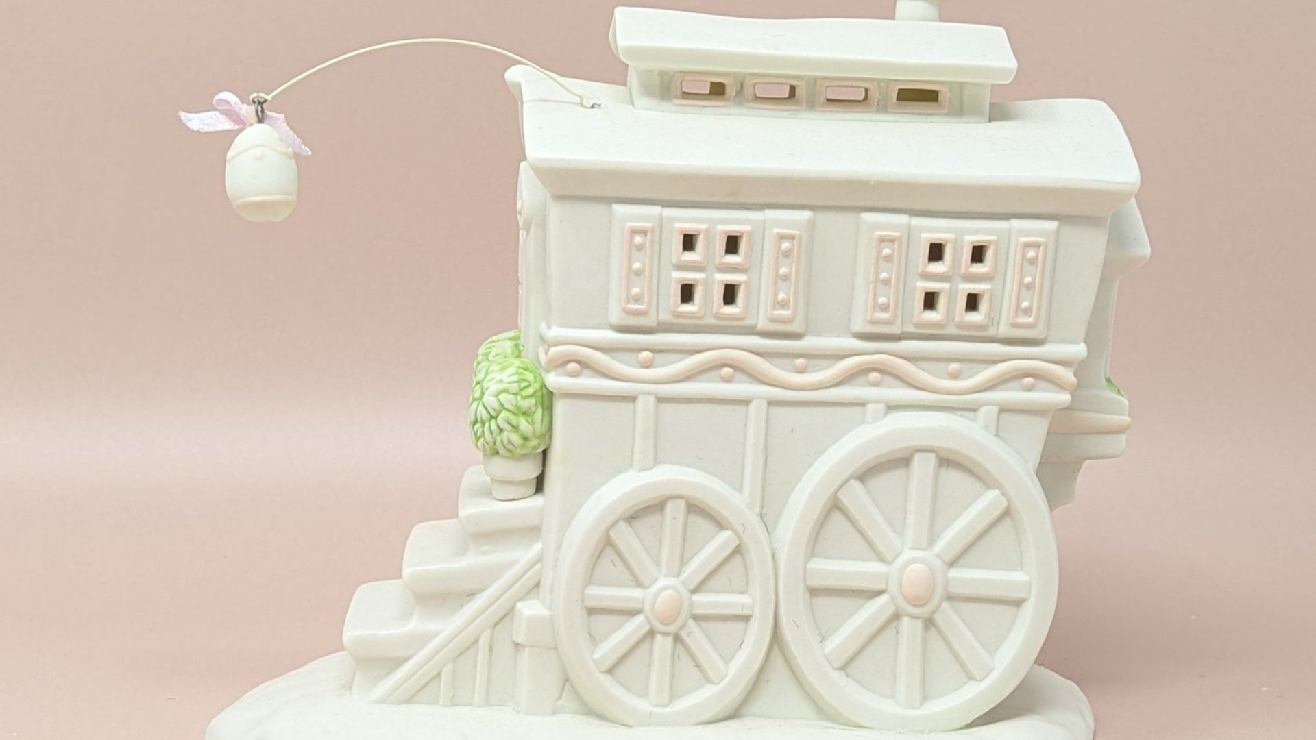 Dept. 56 Snowbunnies "My Woodland Wagon at Turtle Creek." A large, matte bisque porcelain wagon house with pink shutters, oversized wheels, and a hanging porcelain egg lantern. 6.5 inches tall.