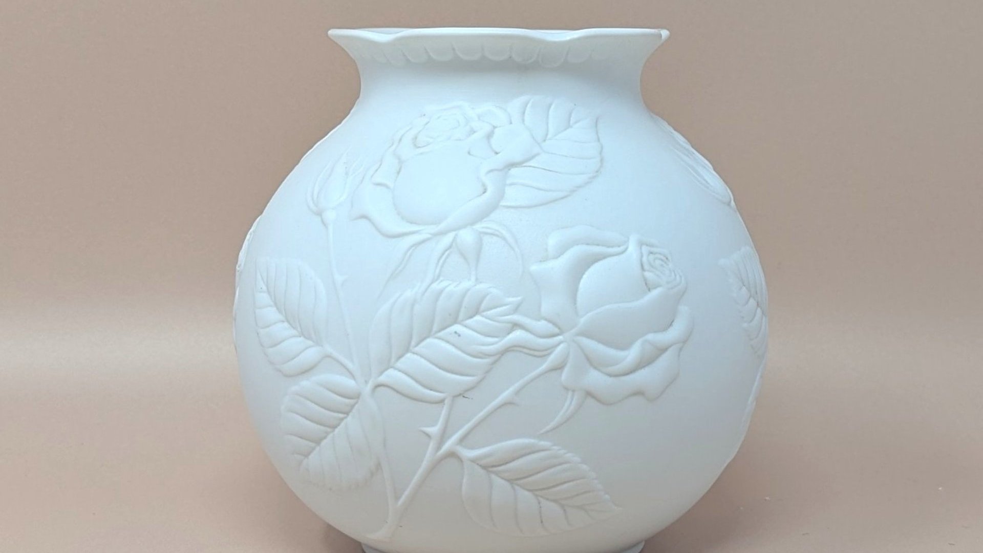 Kaiser West Germany white bisque porcelain vase with a globular body and flared rim. Features a high-relief embossed rose and leaf design with a soft matte finish. 5.5 inches tall.