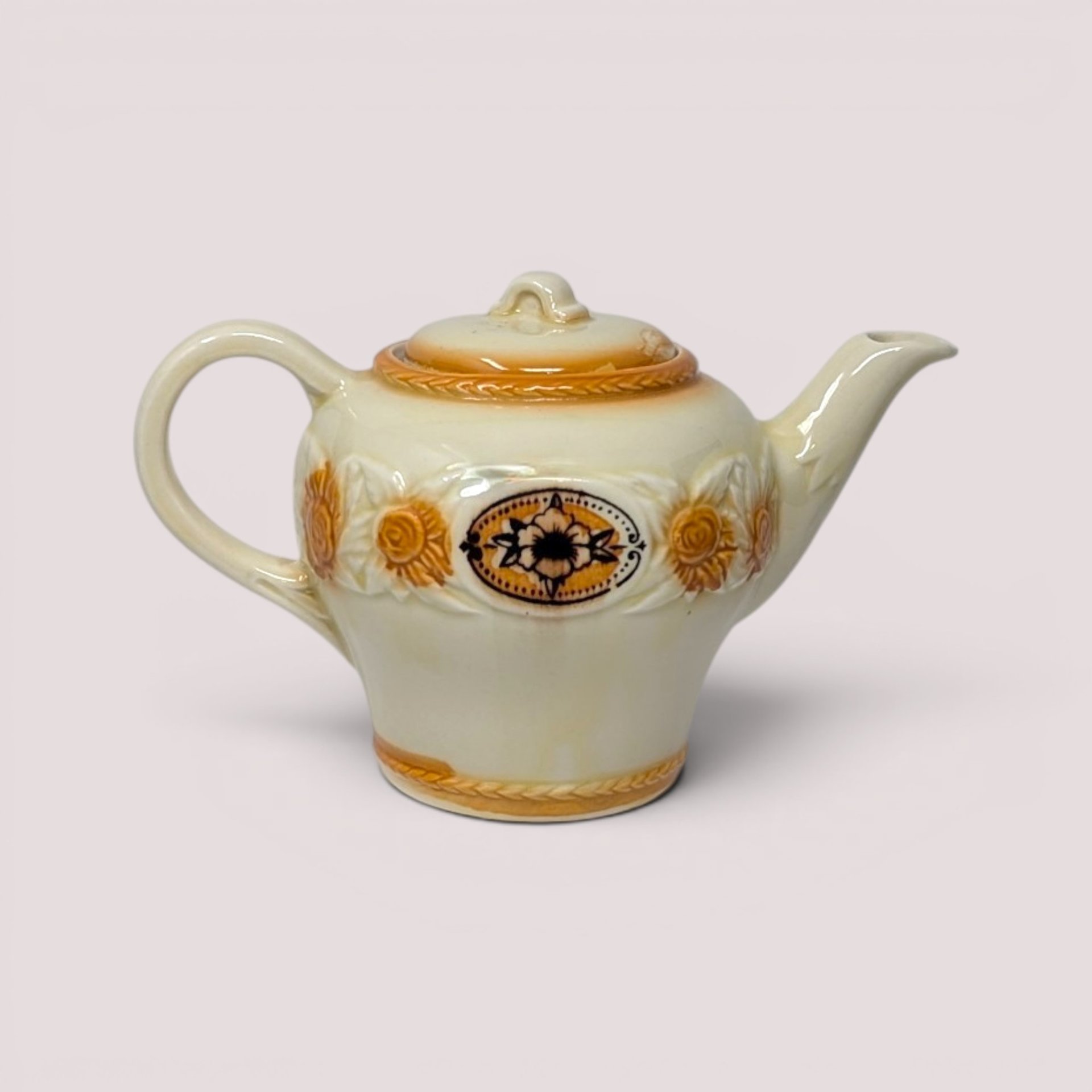 Vintage cream ceramic Porcelier Brown Medallion teapot with lid featuring orange accents and floral motifs.