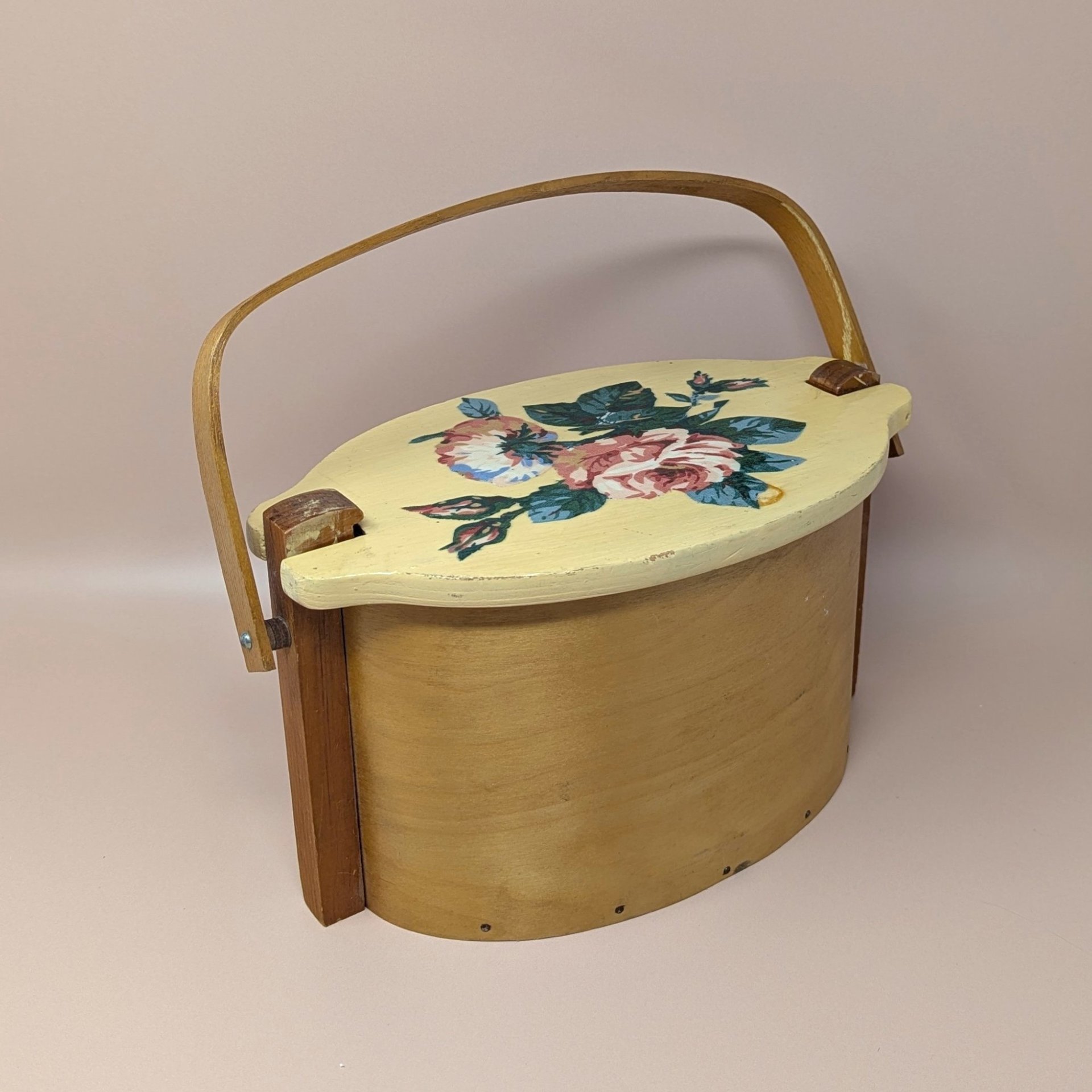 Vintage Basketville wood bucket with a swing handle and fitted lid. Features a hand-painted pink rose and blue floral bouquet on a cream-colored lid. Natural light wood finish. 11.5 inches long.