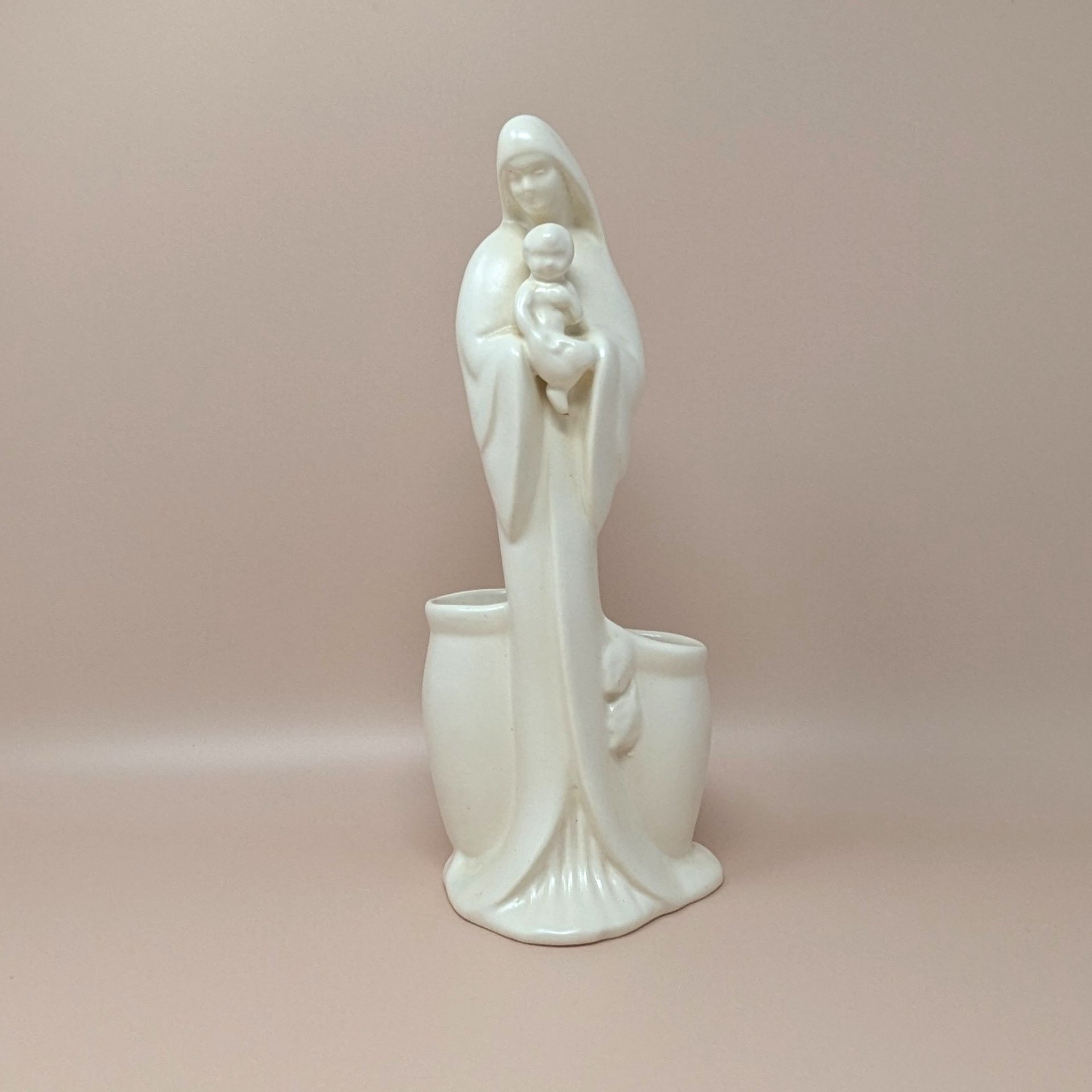 Vintage off-white glazed Haeger ceramic planter featuring a minimalist Madonna holding the infant Christ. Tall, slender silhouette with two integrated planter pockets at the base. 11 inches tall.