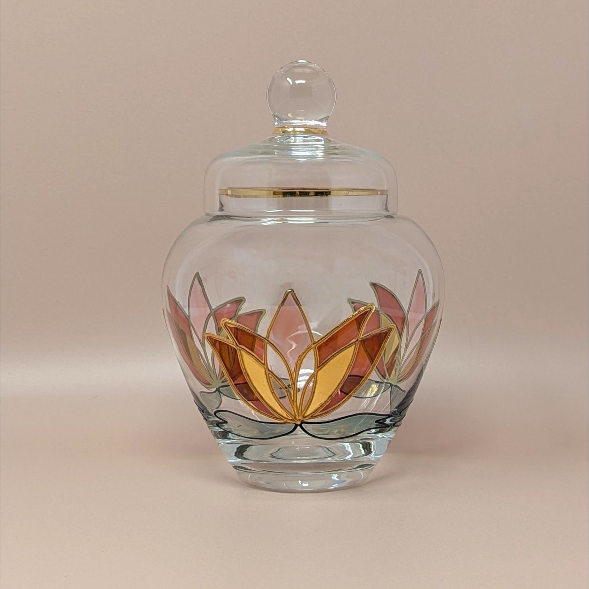 Vintage clear art glass lidded jar with a colorful stained-glass style lotus flower. Features pink, orange, and gold petals with black outlines and a gold-rimmed lid. 7.75 inches tall.