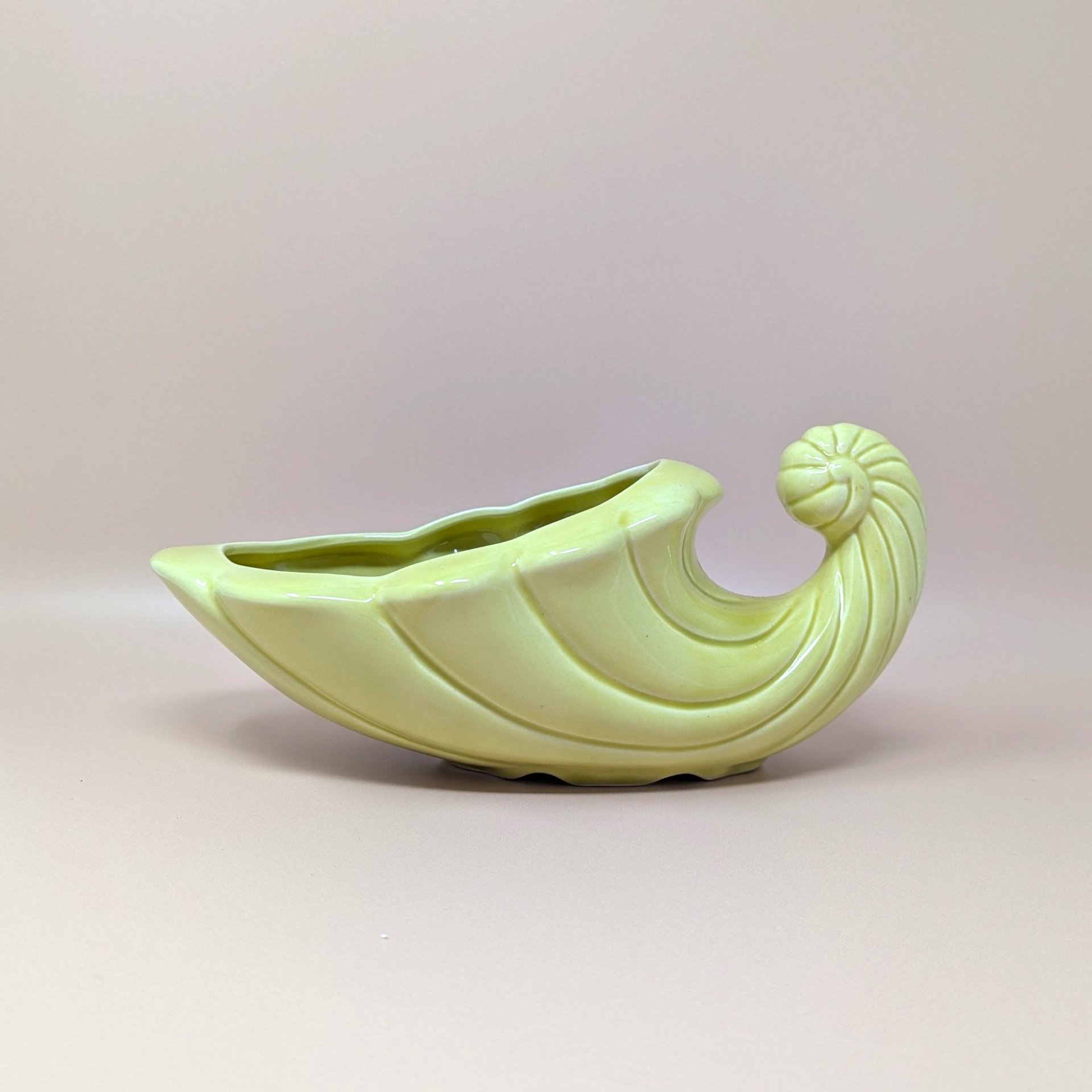 Vintage mid-century cornucopia planter in a soft pastel yellow. Features a sculptural "horn of plenty" design with swirled ridges and a curled tail. 11 inches long.