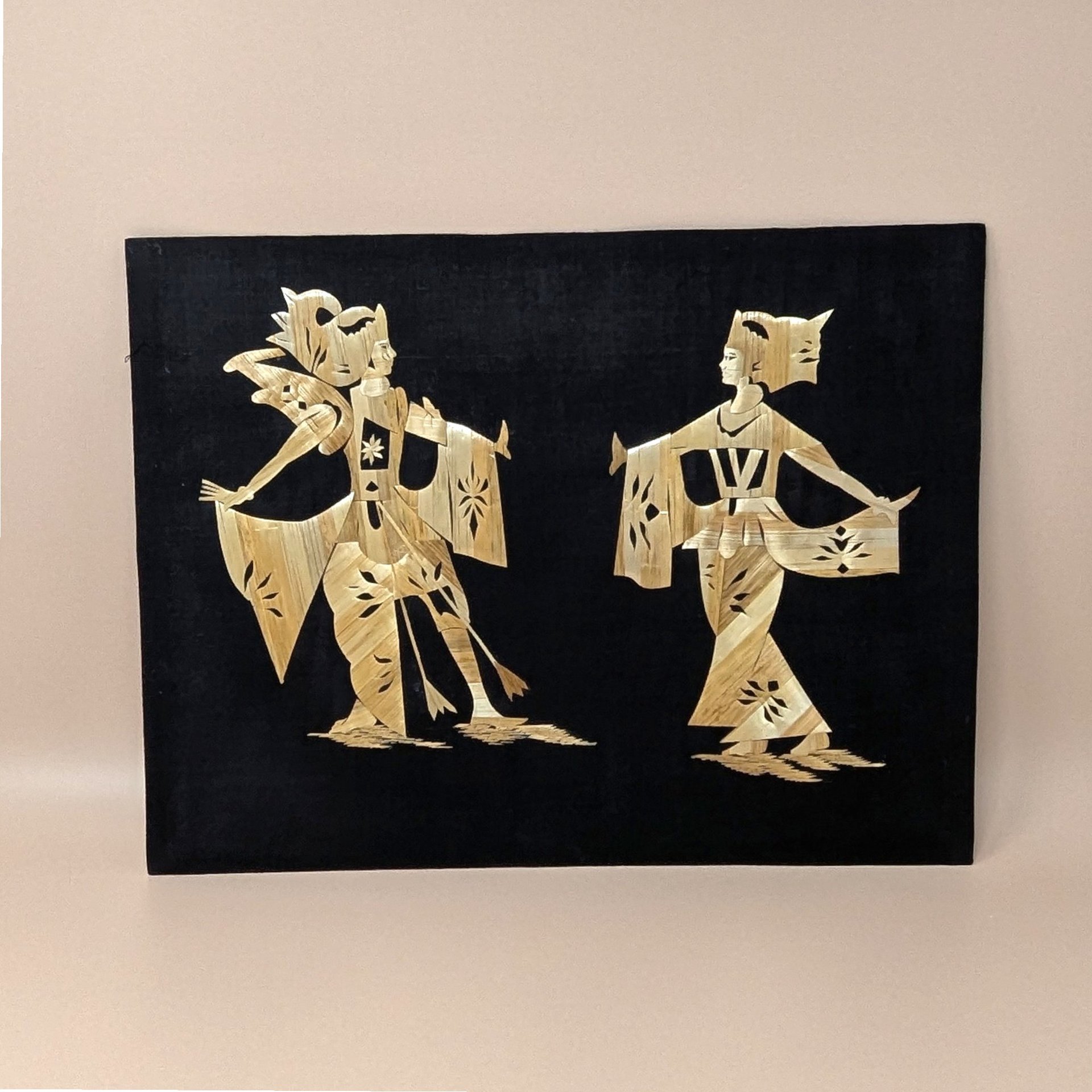 Vintage Asian folk art picture made of shimmering golden wheat straw. Features a man and woman in traditional ceremonial dress on a black fabric background. 11.5 by 15 inches.