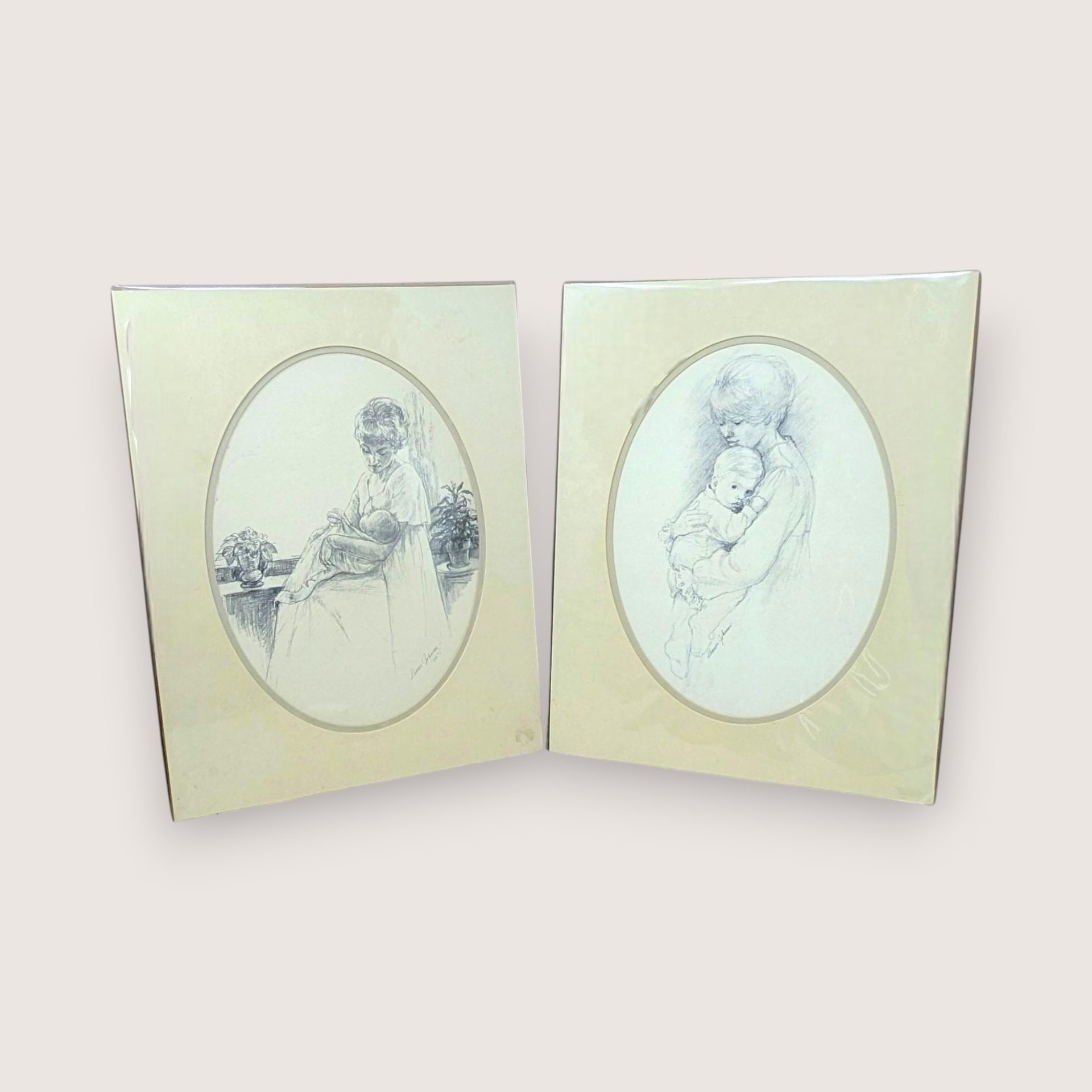 Pair of vintage 1975 Sharon Johnson prints. Fine charcoal-style drawings of a mother nursing a baby and a mother holding a child. Oval mattes on cream paper. 14x11 inches.