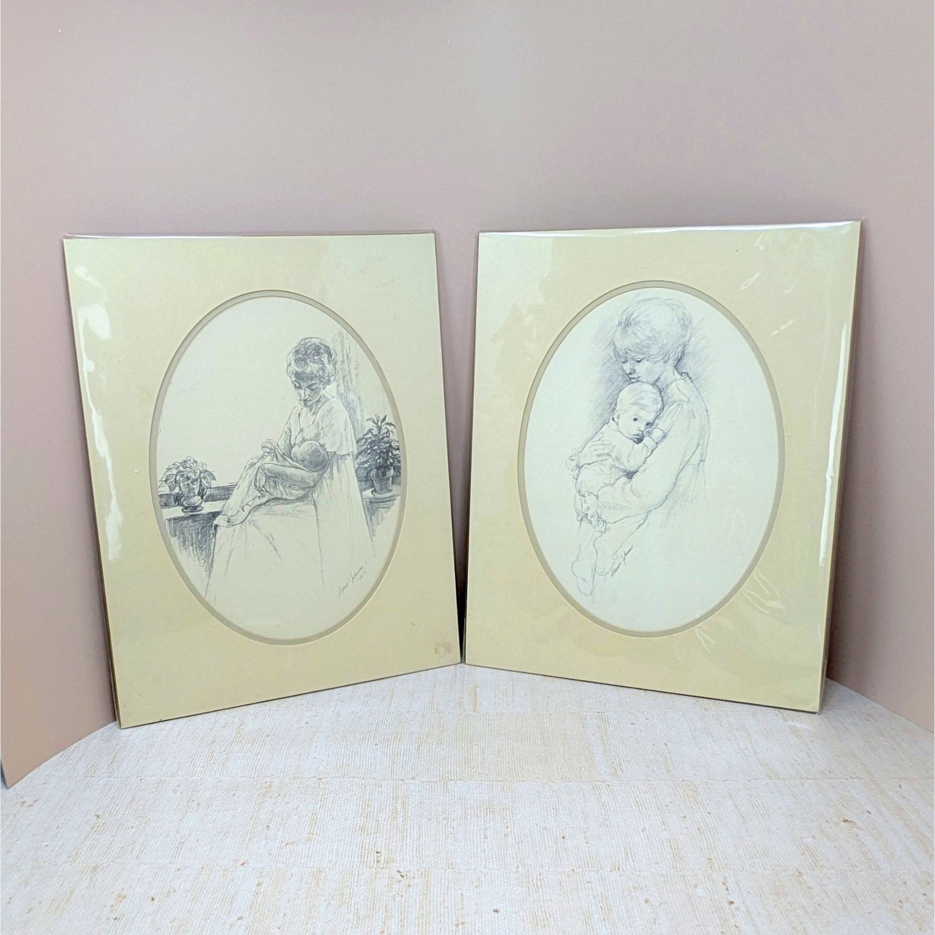 Pair of vintage 1975 Sharon Johnson prints. Fine charcoal-style drawings of a mother nursing a baby and a mother holding a child. Oval mattes on cream paper. 14x11 inches.