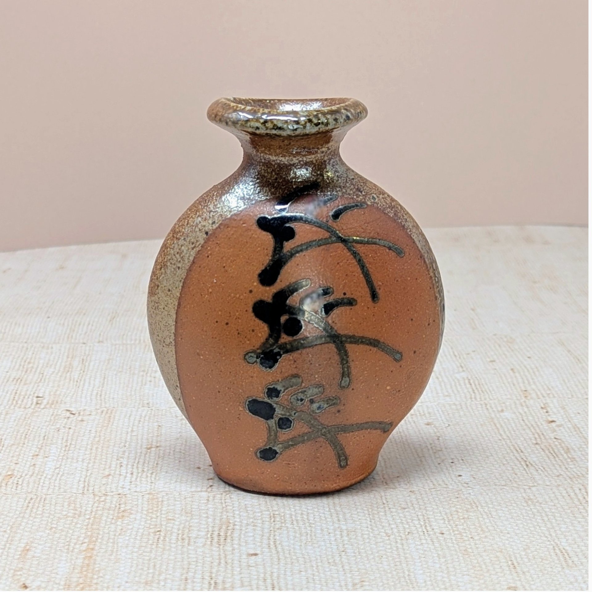 Vintage Brad Lee Henry studio pottery vase. Features a bulbous body in earthy red-brown with a metallic tenmoku drip glaze and black calligraphic slip-painted accents. 5 inches tall.