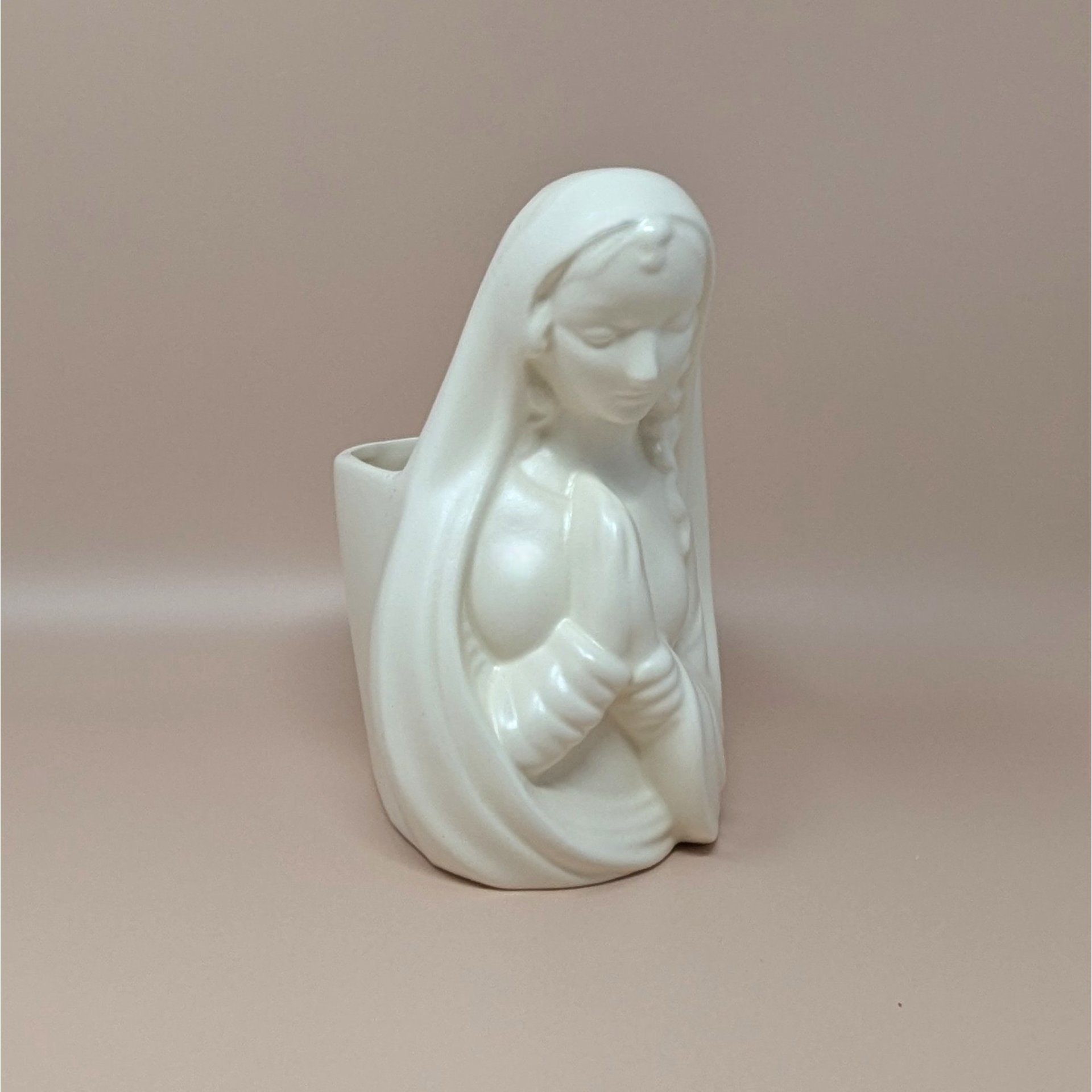 Mid-century white ceramic planter featuring a bust of a praying Madonna. Smooth, semi-matte ivory finish, flowing drapery, and serene facial expression. Hollow back for plants or stems.