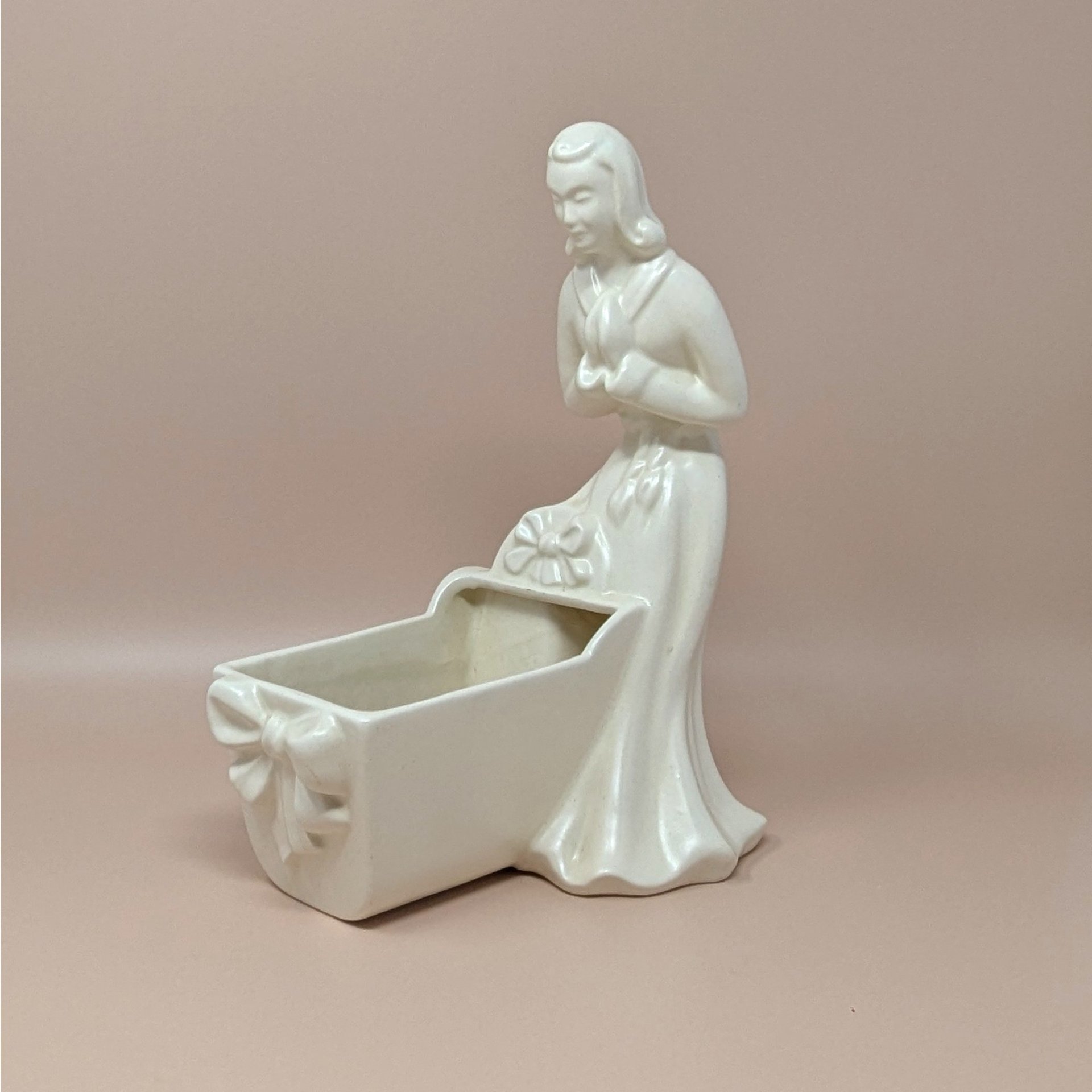 Vintage Royal Haeger white pottery planter featuring a colonial-style woman in a flowing dress leaning over a baby cradle. High-gloss "Alabaster" white glaze. 11 inches tall.
