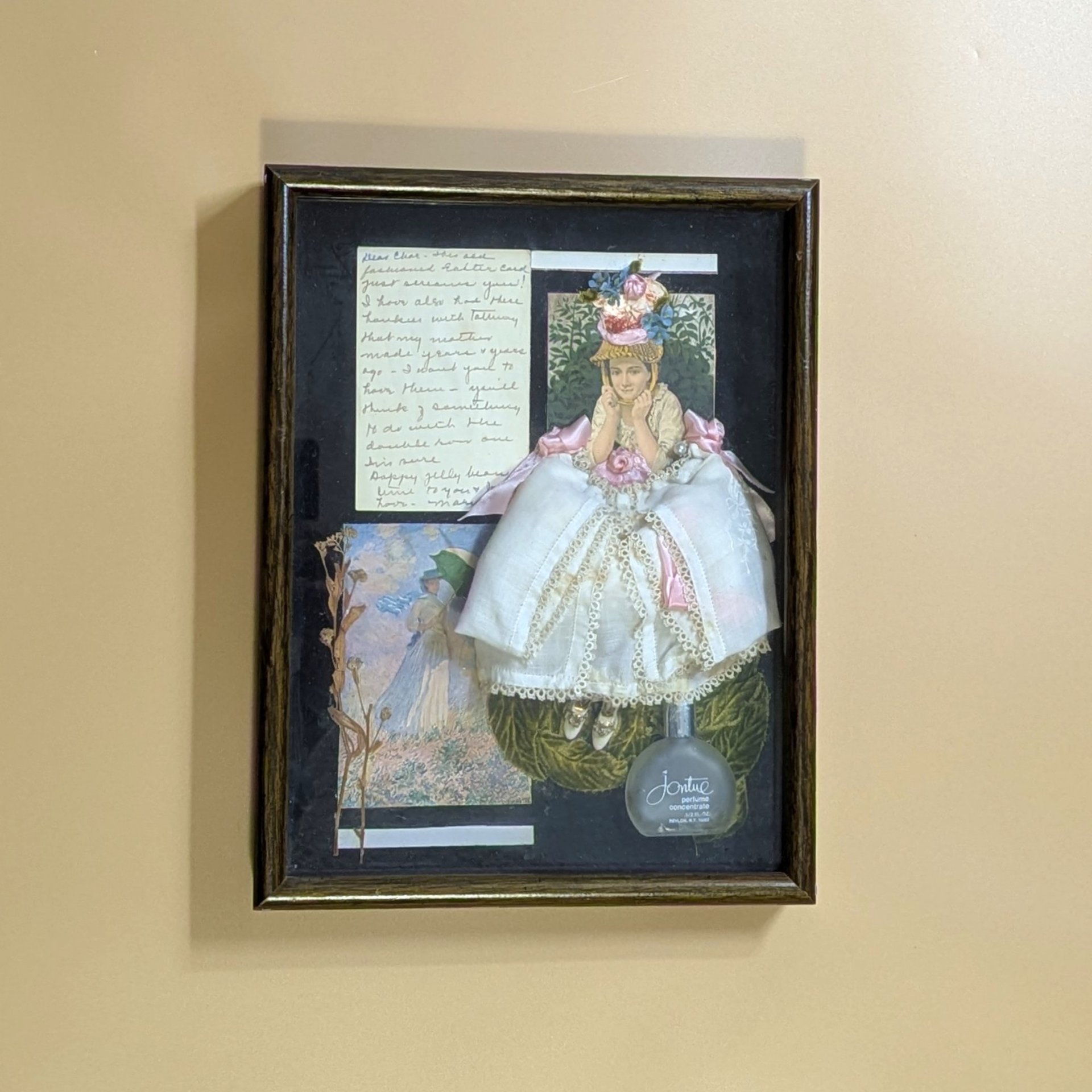 Dark wood shadow box featuring a 3D collage of a Victorian woman in a white lace dress. Black background with a frosted perfume bottle, dried botanicals, and handwritten yellowed paper. Rich, layered multimedia textures.