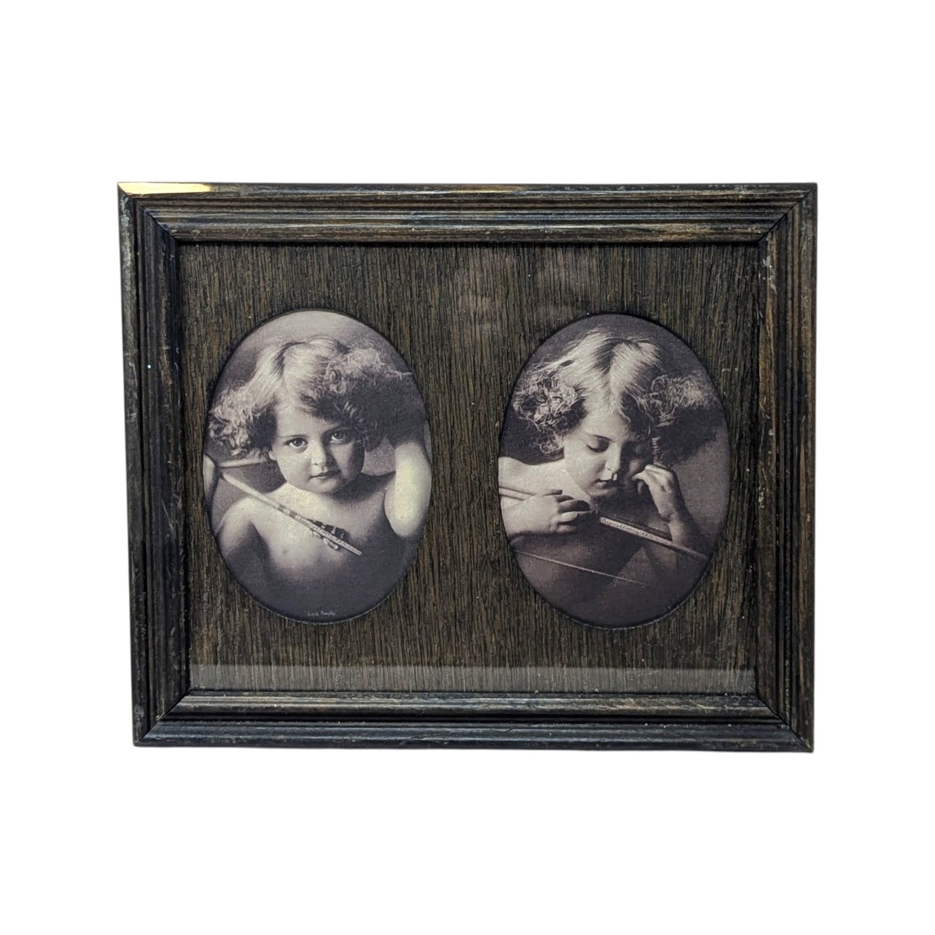 A dark wood frame with two oval cutouts. Inside are sepia-toned prints of a young child with curly hair and wings, depicting "Angel Awake" looking at the viewer and "Angel Asleep" with eyes closed. Rustic wood grain texture.
