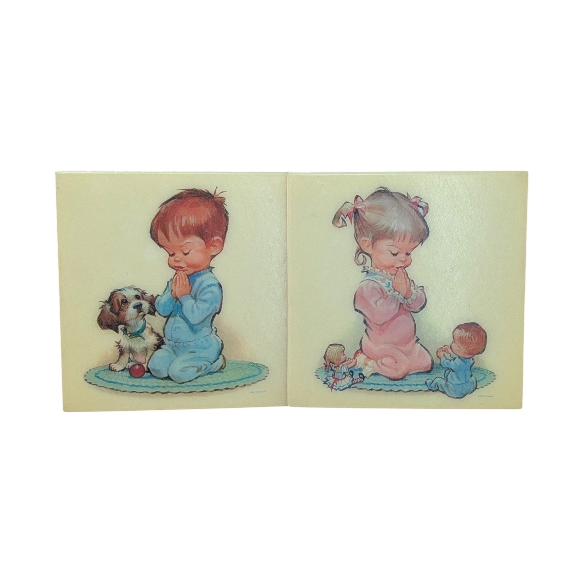A pair of square fiberglass wall plaques with cream backgrounds. One features a young girl in pink pajamas praying, and the other shows a boy in blue pajamas praying with a small puppy. Soft, mid-century illustrated style.