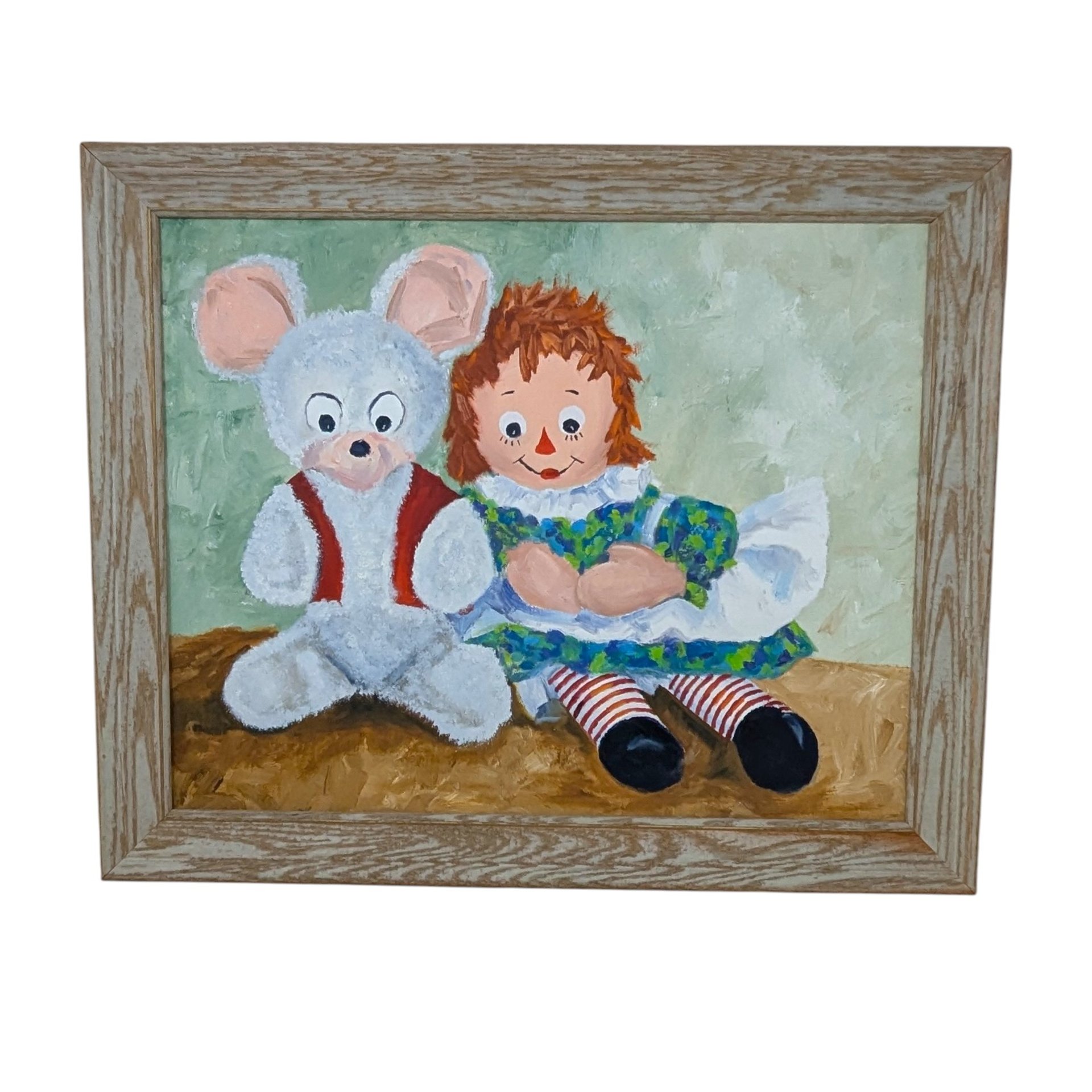 A large horizontal painting on canvas board featuring Raggedy Ann sitting next to a white teddy bear in a red vest. Impasto brushstrokes in shades of green and brown. Housed in a light wood grain frame.