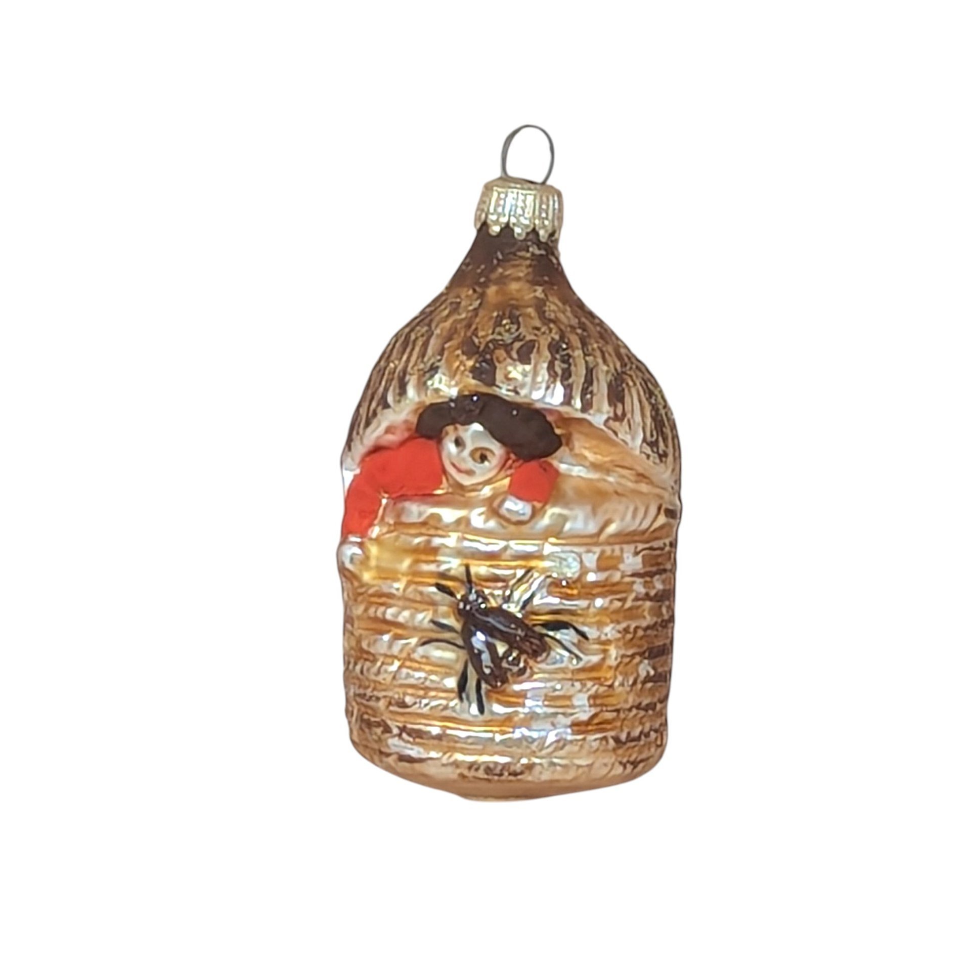 A vertical 4.5-inch vintage blown glass ornament shaped like a beehive. A hand-painted baby with a red suit peeks from the top, and a large brown bee is featured on the front. Silvered glass with gold glitter accents.