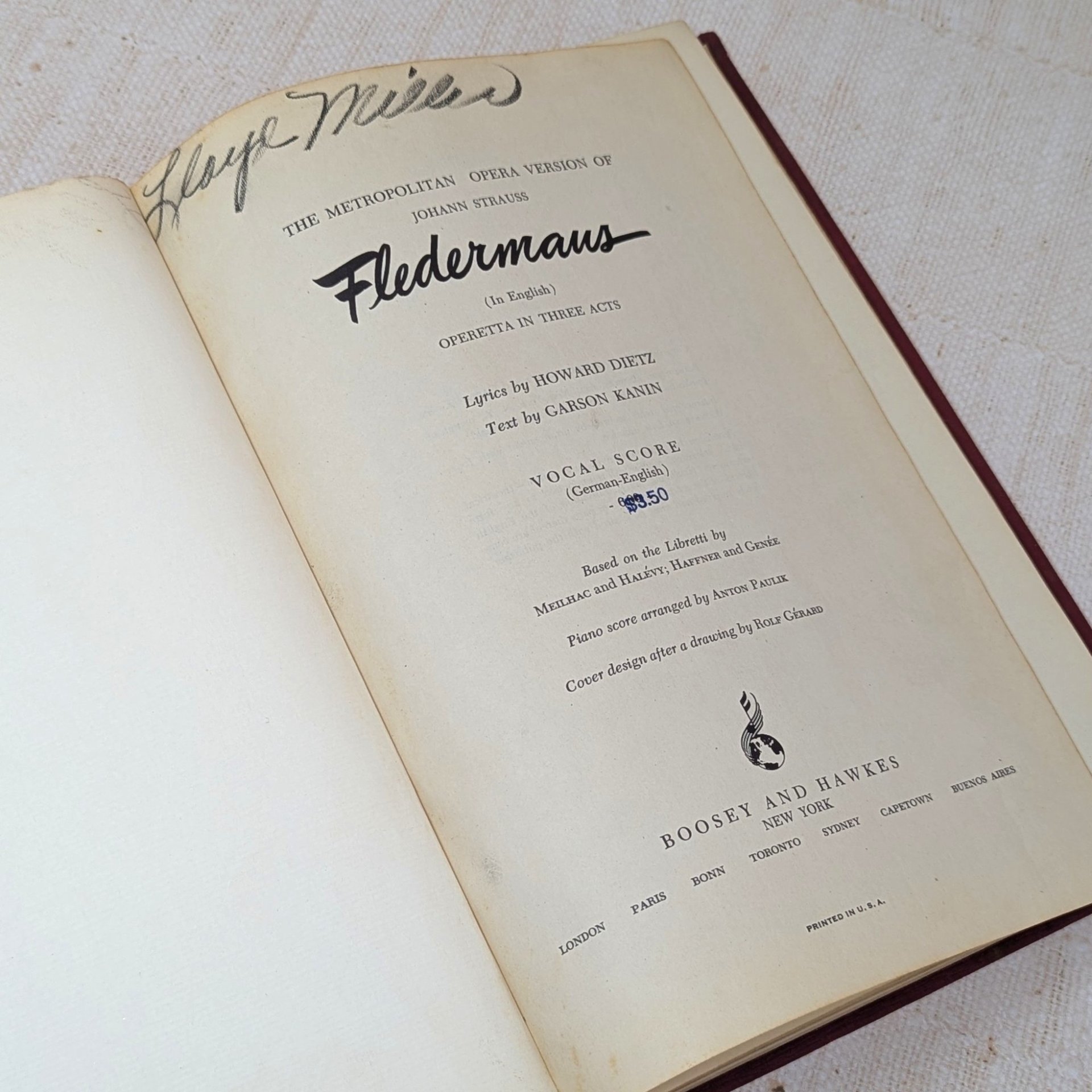 A vintage musical score book titled Fledermaus by Johann Strauss. The title page features elegant black typography and a handwritten signature at the top. The paper shows a warm, aged patina consistent with its mid-century origin.