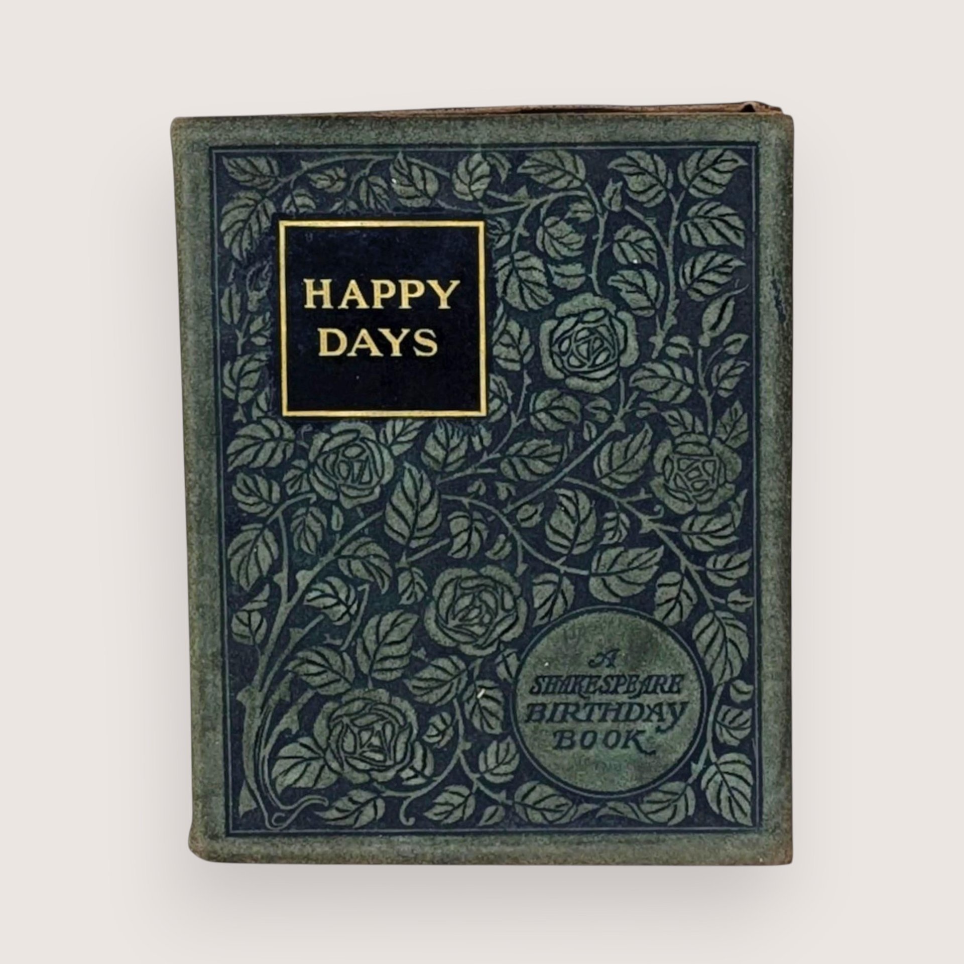 Antique green book cover titled "Happy Days A Shakespeare Birthday Book" with an intricate rose and leaf pattern.
