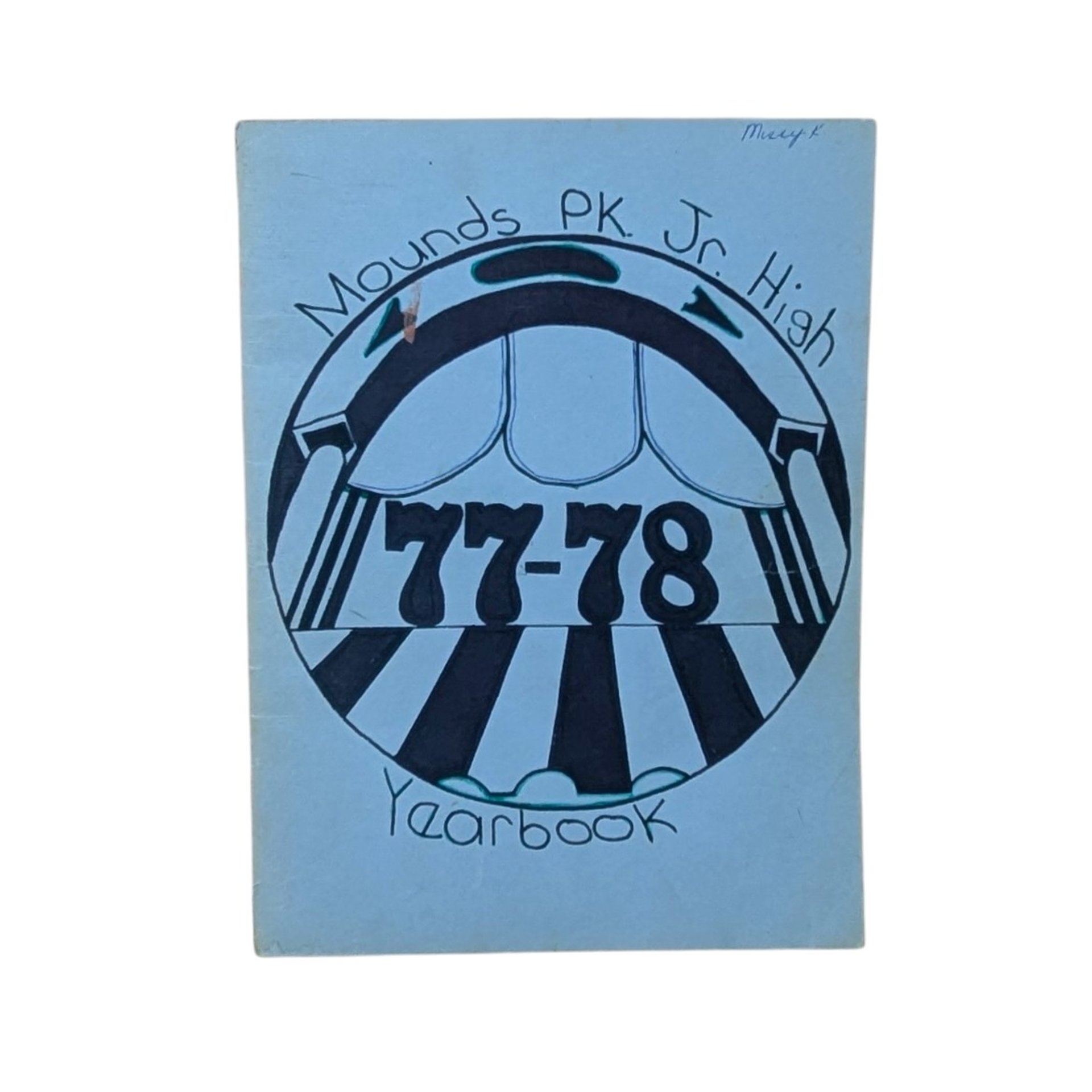A vintage softcover yearbook featuring a light blue cover with a hand-drawn circular graphic in black ink. The center shows the bold numbers 77-78 under a theatrical or arched motif. A name is written in small ink at the top right.