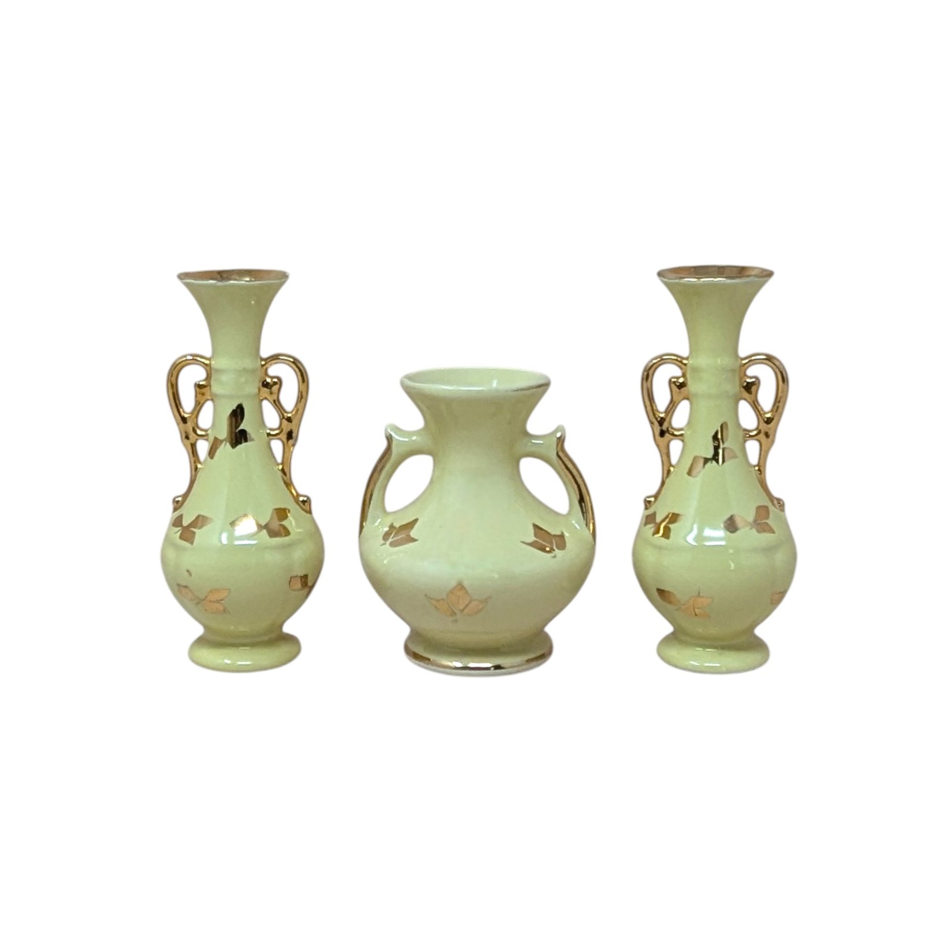 A collection of four vintage yellow ceramic vessels with bright gold accents. Includes a matching trio of Art Deco style vases with handles and gold leaf motifs, and a single rounded pitcher-style bud vase featuring a raised gold rose design.