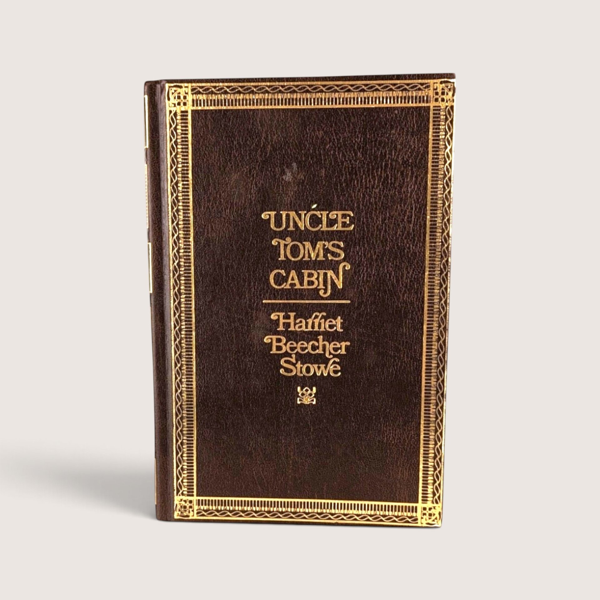 Vintage 1976 hardcover edition of Uncle Tom's Cabin by Harriet Beecher Stowe with faux-leather and gold stamped cover.