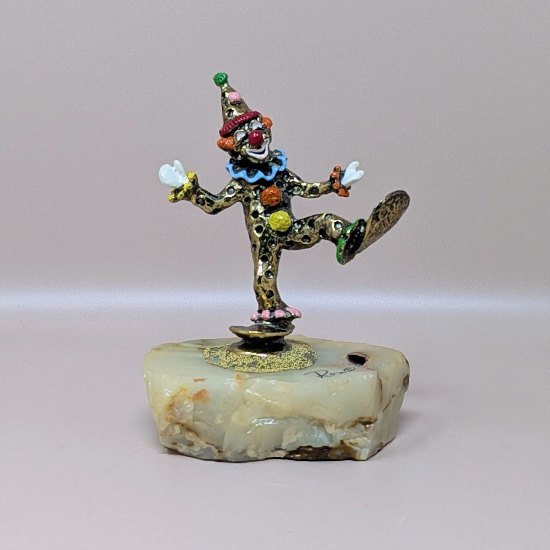 A hand-painted metal clown figurine by Ron Lee with 24k gold plating on a thick, natural onyx marble base against a neutral background.