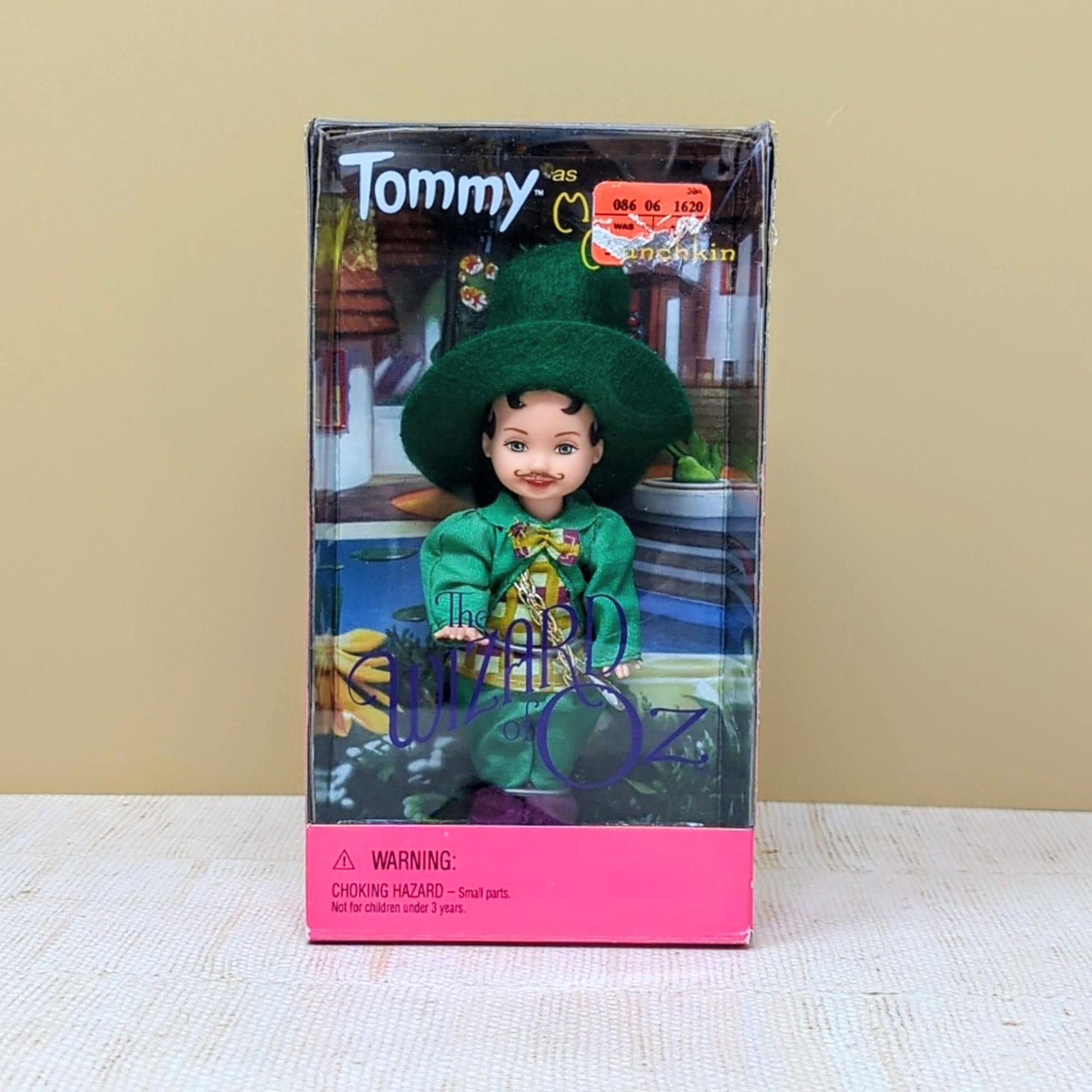 A 4.5-inch Tommy doll dressed as the Mayor Munchkin in a green jacket and hat, displayed inside its original 1999 Wizard of Oz themed window box.