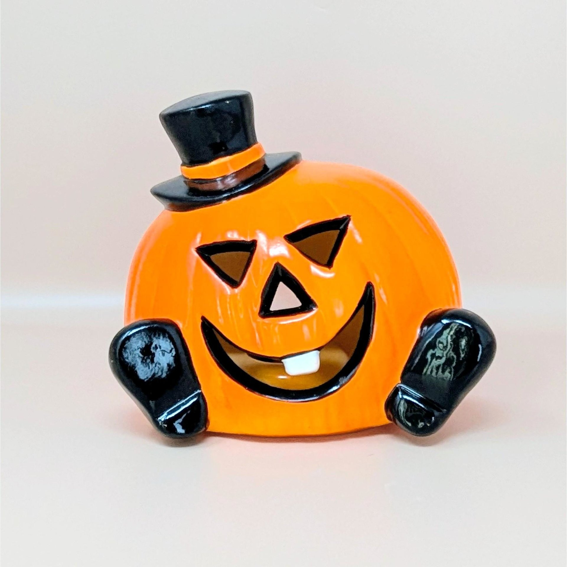 A glossy orange ceramic pumpkin figurine wearing a black top hat and featuring a single white tooth against a neutral background.