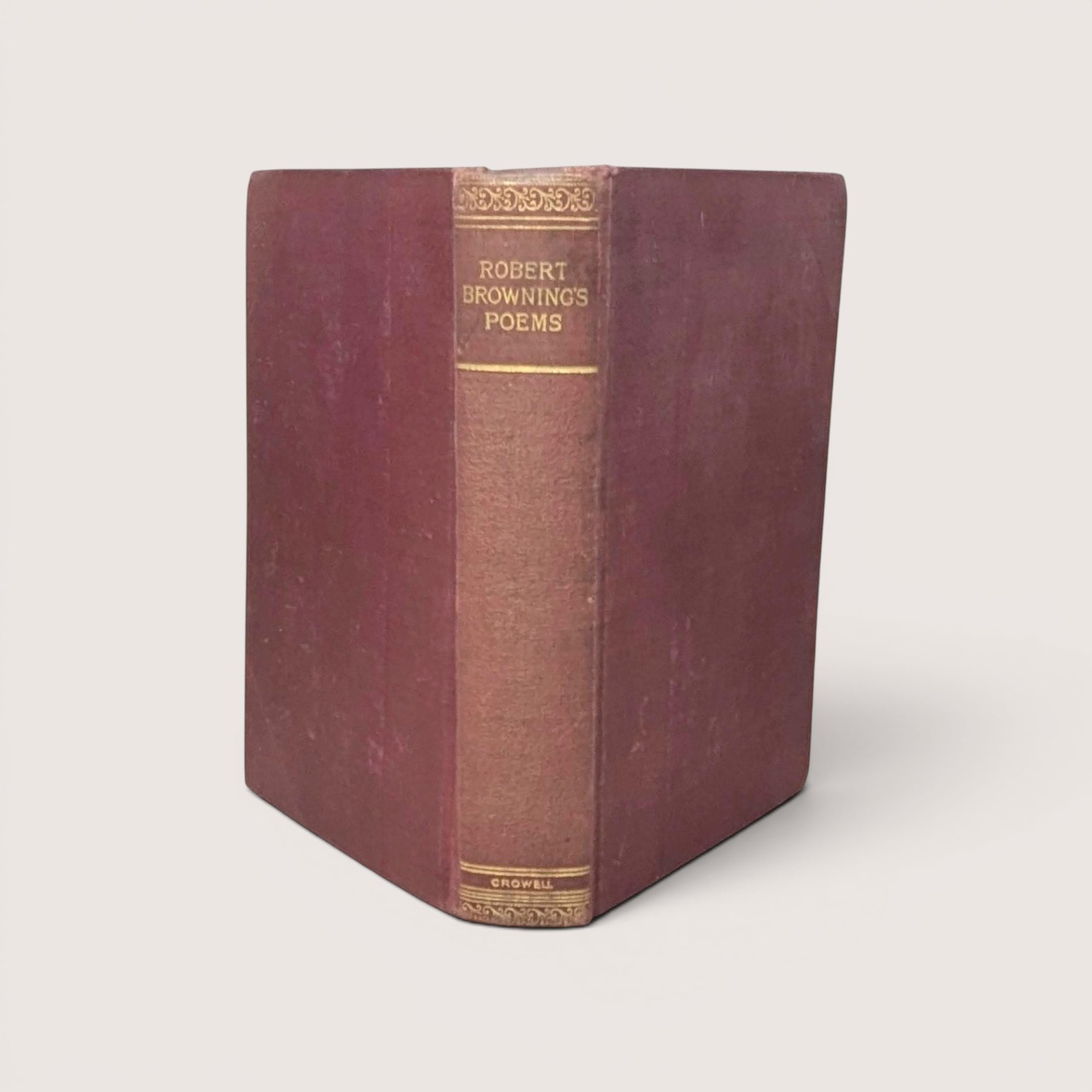 A burgundy cloth-bound hardcover book standing upright, featuring gilded typography on the spine for Robert Browning's Poems against a neutral background.