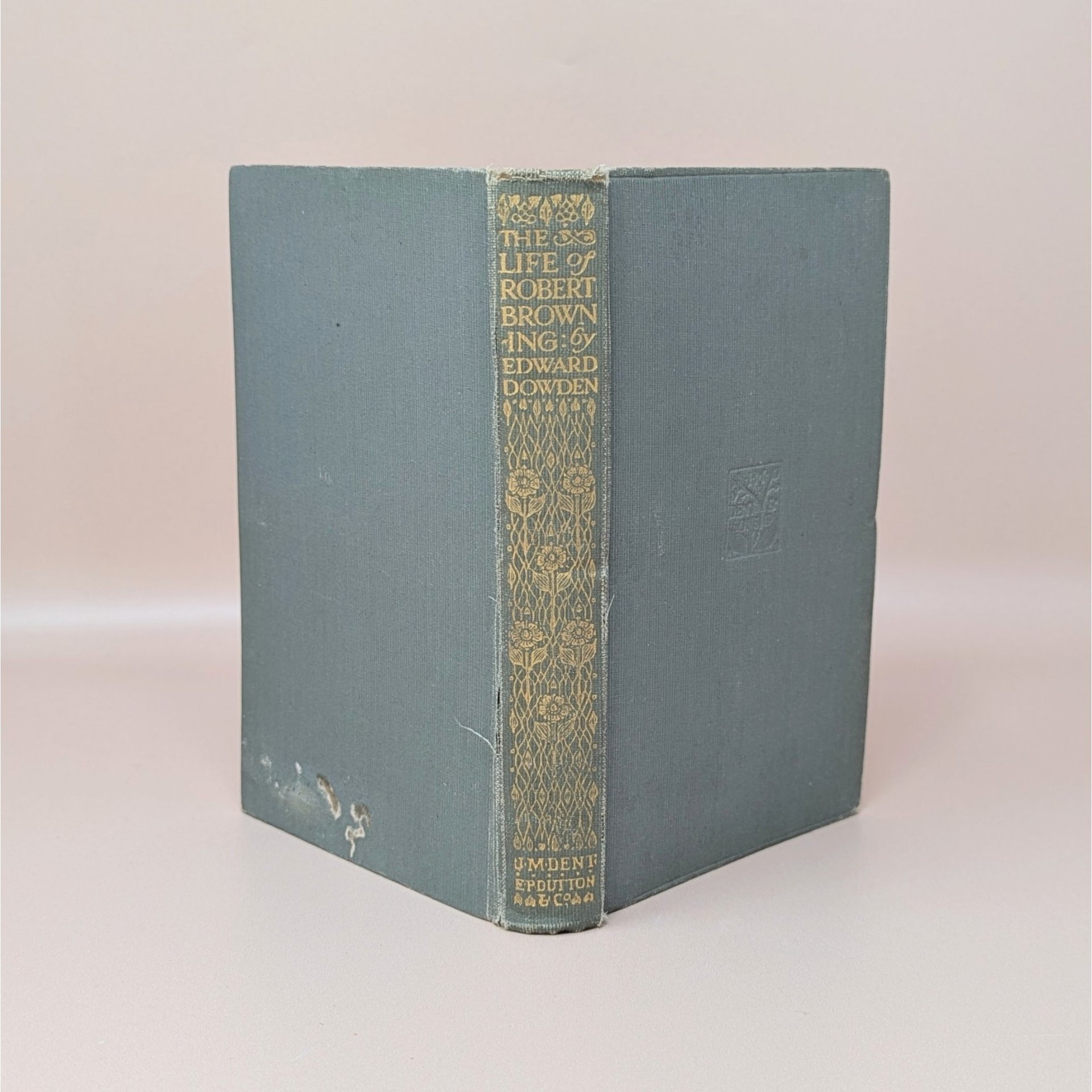 A slate blue cloth-bound hardcover book standing upright, featuring an ornate gilded spine with floral patterns and typography for The Life of Robert Browning by Edward Dowden.