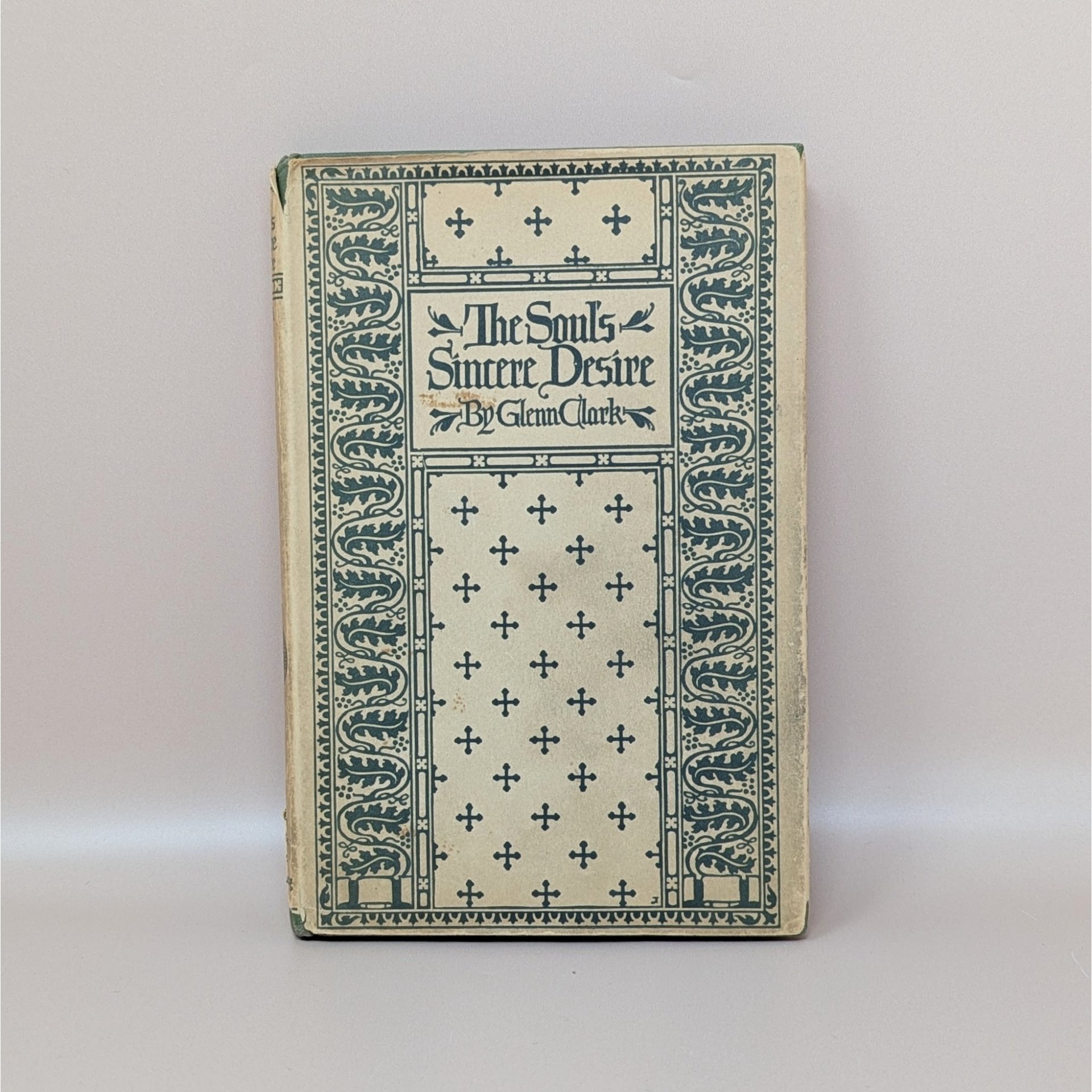 A vintage hardcover book with a cream and teal green patterned cover featuring crosses and floral borders, titled The Soul's Sincere Desire by Glenn Clark.