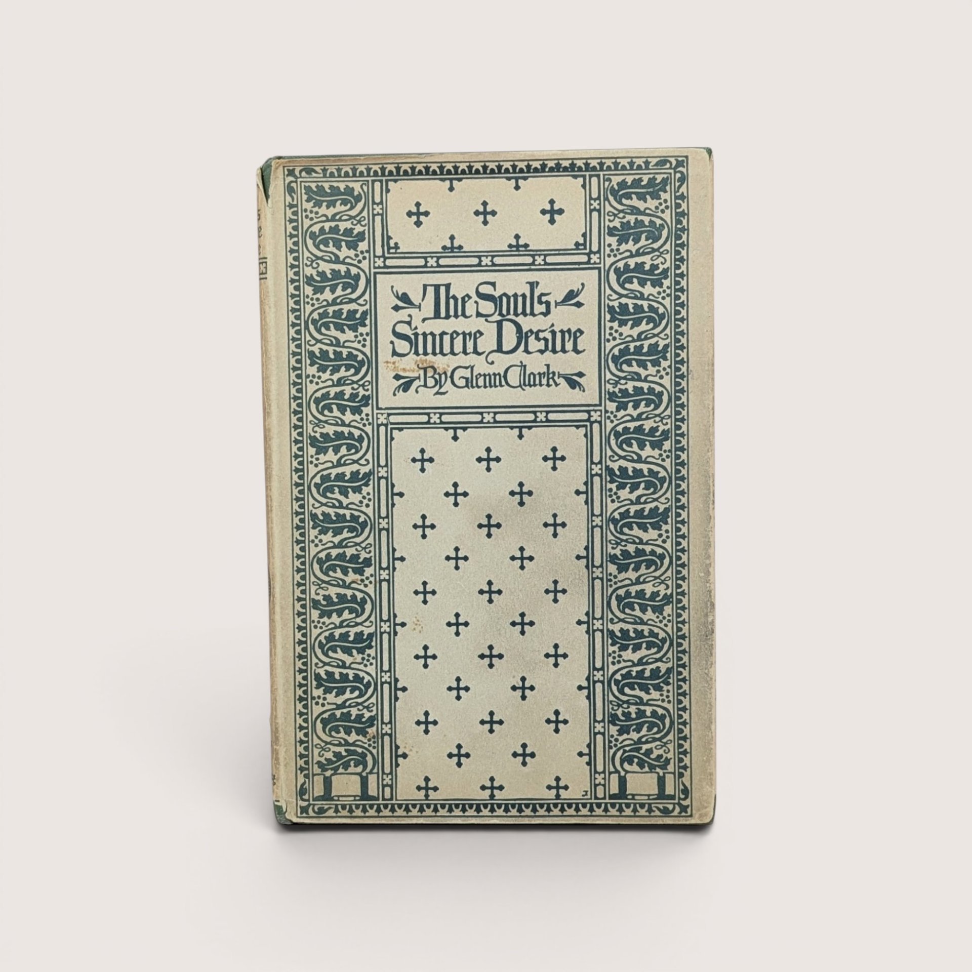 A vintage hardcover book with a cream and teal green patterned cover featuring crosses and floral borders, titled The Soul's Sincere Desire by Glenn Clark.