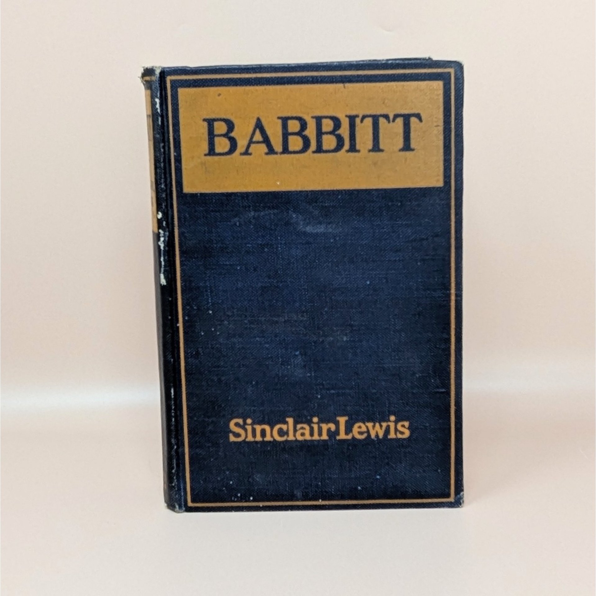 A 1922 hardcover copy of Babbitt by Sinclair Lewis, featuring a dark navy blue cloth cover with gold lettering and a simple rectangular border.