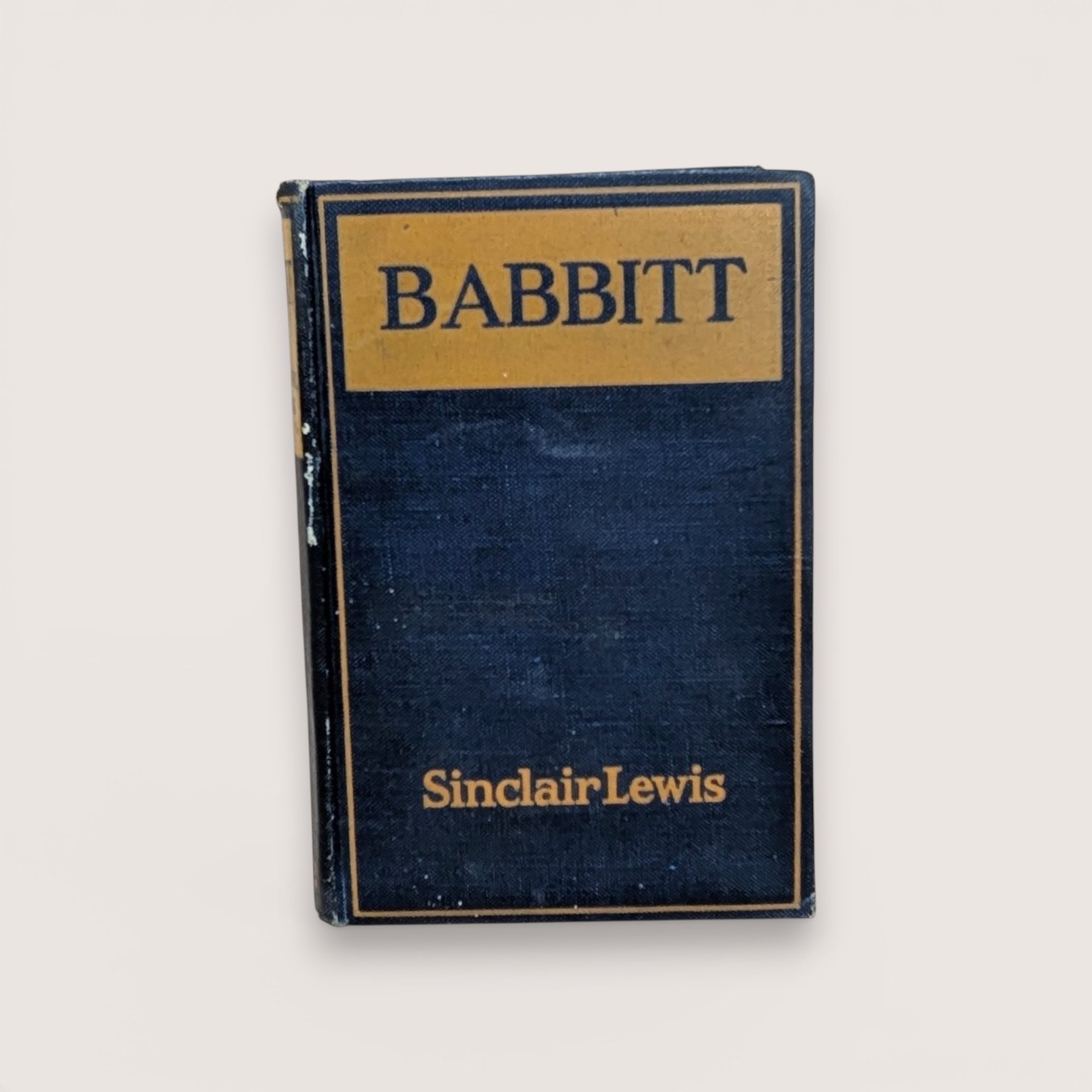 A 1922 hardcover copy of Babbitt by Sinclair Lewis, featuring a dark navy blue cloth cover with gold lettering and a simple rectangular border.