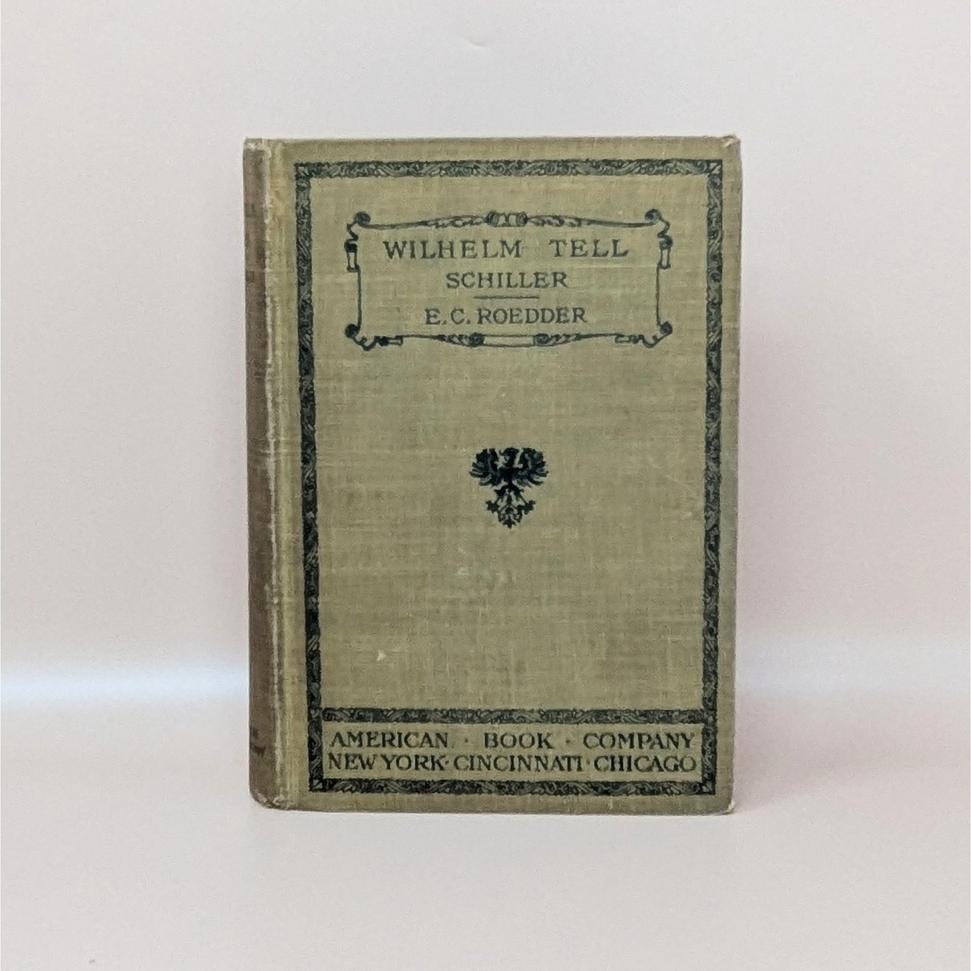 A 1905 hardcover copy of Wilhelm Tell by Schiller, featuring an olive green cloth cover with black ornamental borders and a central heraldic eagle crest.