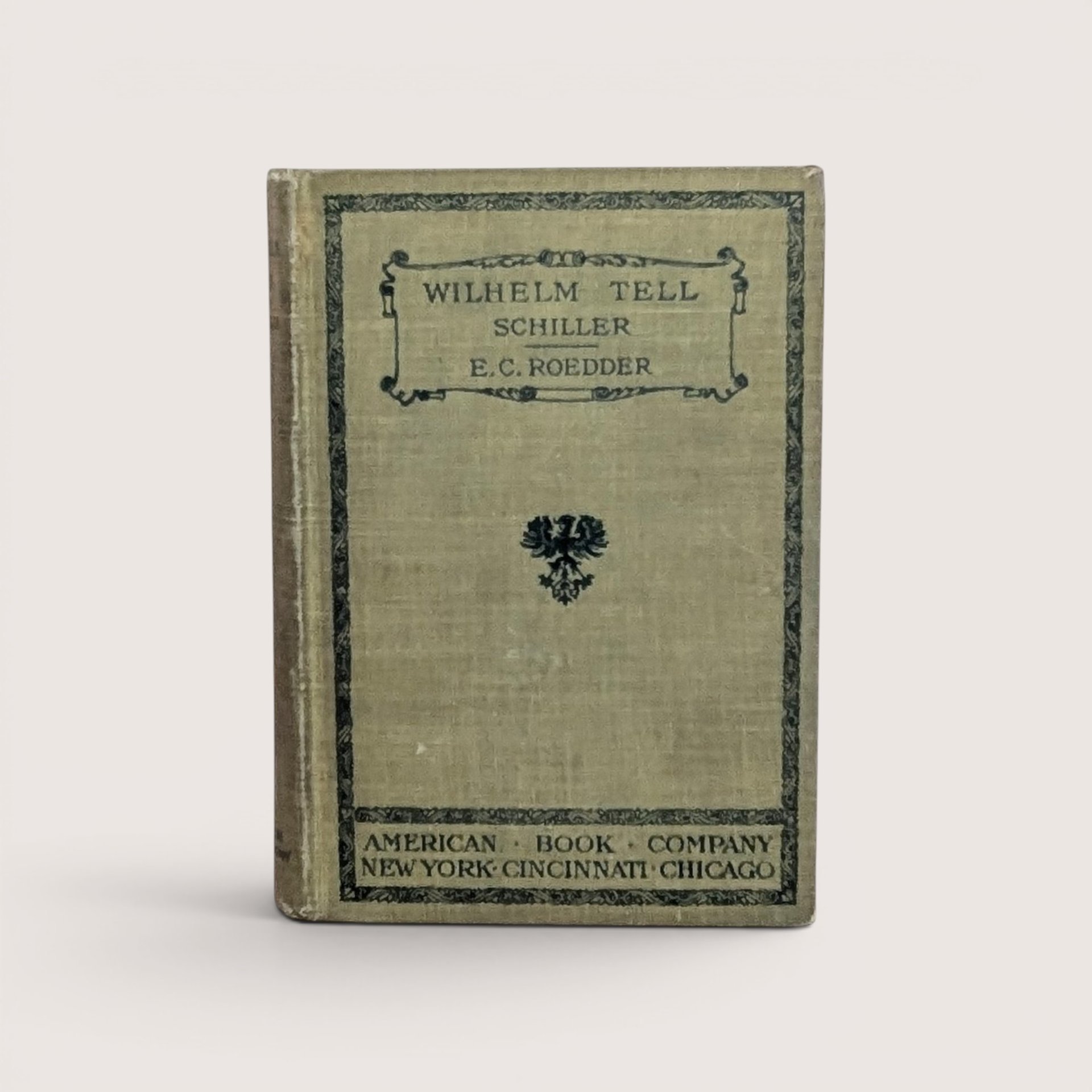 A 1905 hardcover copy of Wilhelm Tell by Schiller, featuring an olive green cloth cover with black ornamental borders and a central heraldic eagle crest.