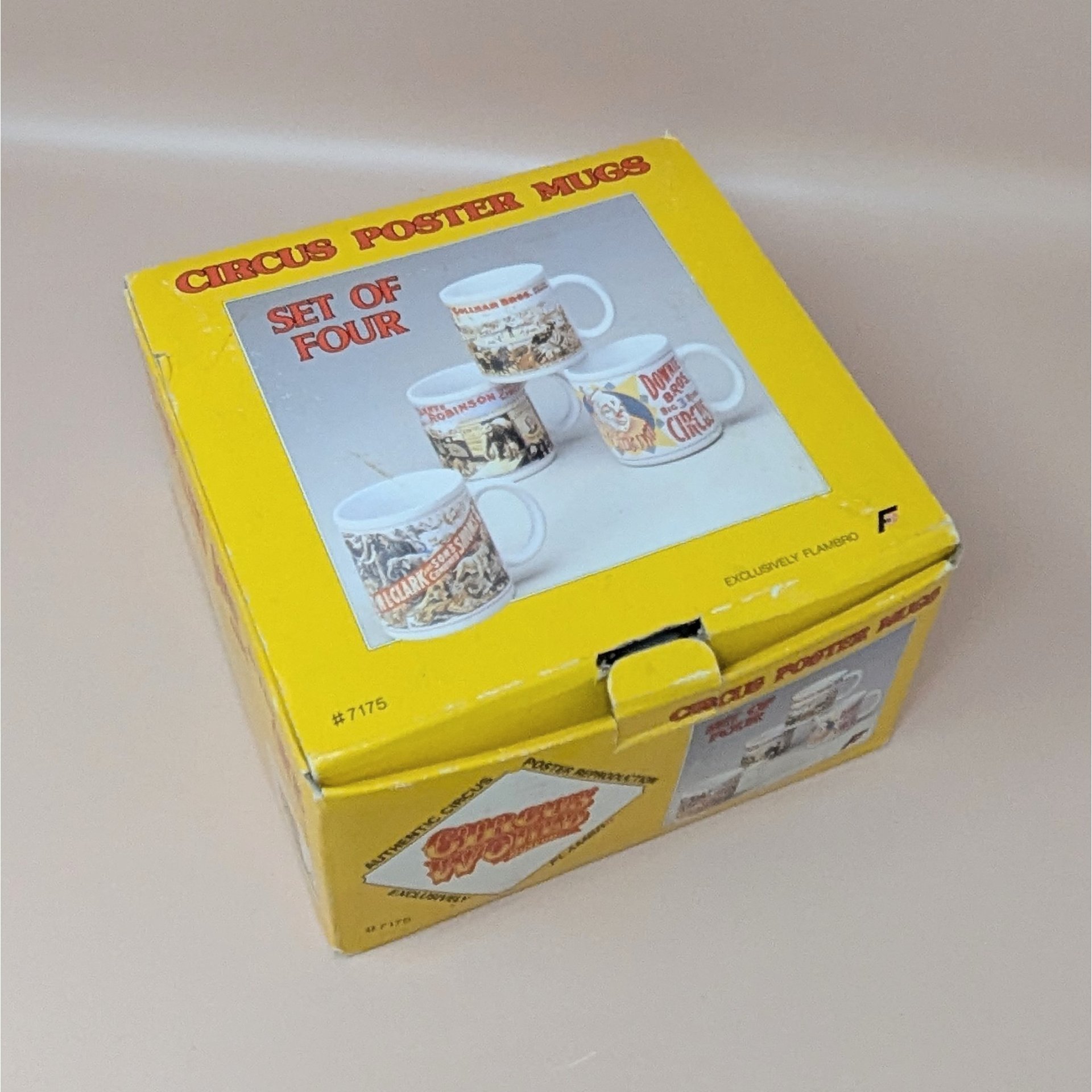 A yellow vintage box containing a set of four white ceramic mugs, each featuring a different colorful vintage circus poster illustration.