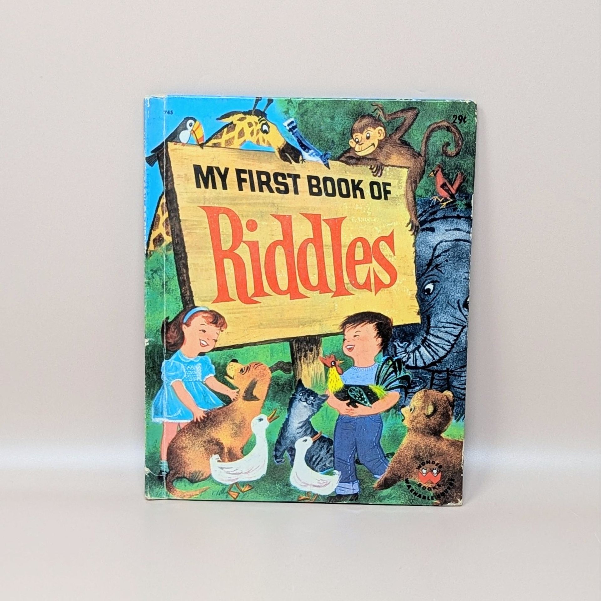 A vintage 1960 children's book titled My First Book of Riddles featuring a colorful cover with animals and two children holding a rooster and a duck