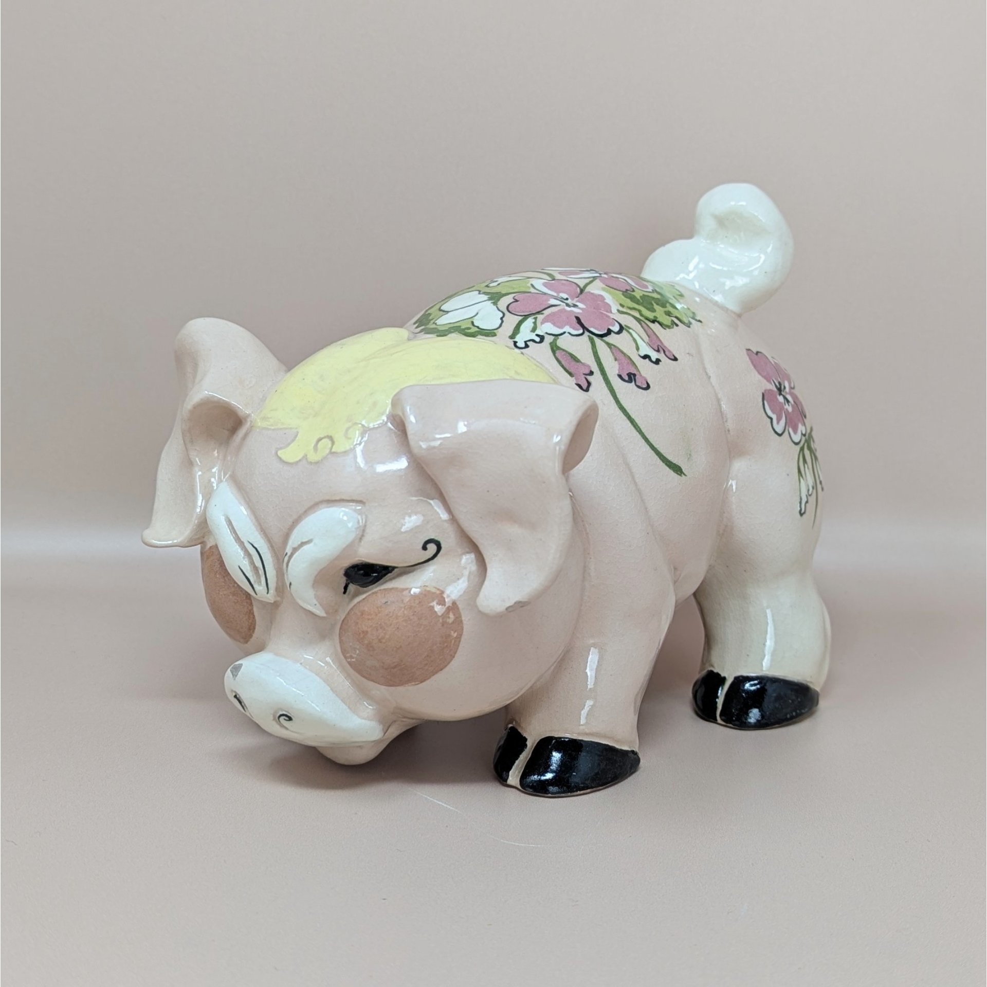A vintage Kay Finch California pottery pig figurine with a pink floral pattern on its back and a humorous grumpy facial expression.