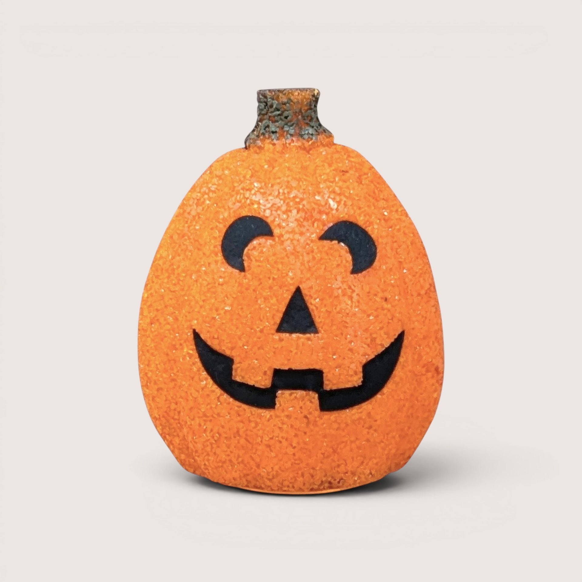 A vintage orange melted plastic "popcorn" Jack O'Lantern light with a smiling black face and a green stem on top.
