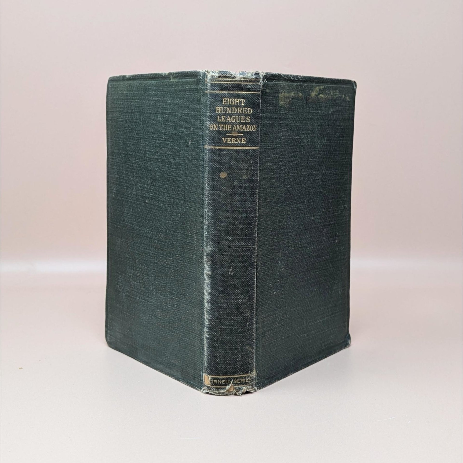 An antique forest green hardcover book titled Eight Hundred Leagues on the Amazon by Jules Verne with gold lettering on a worn spine