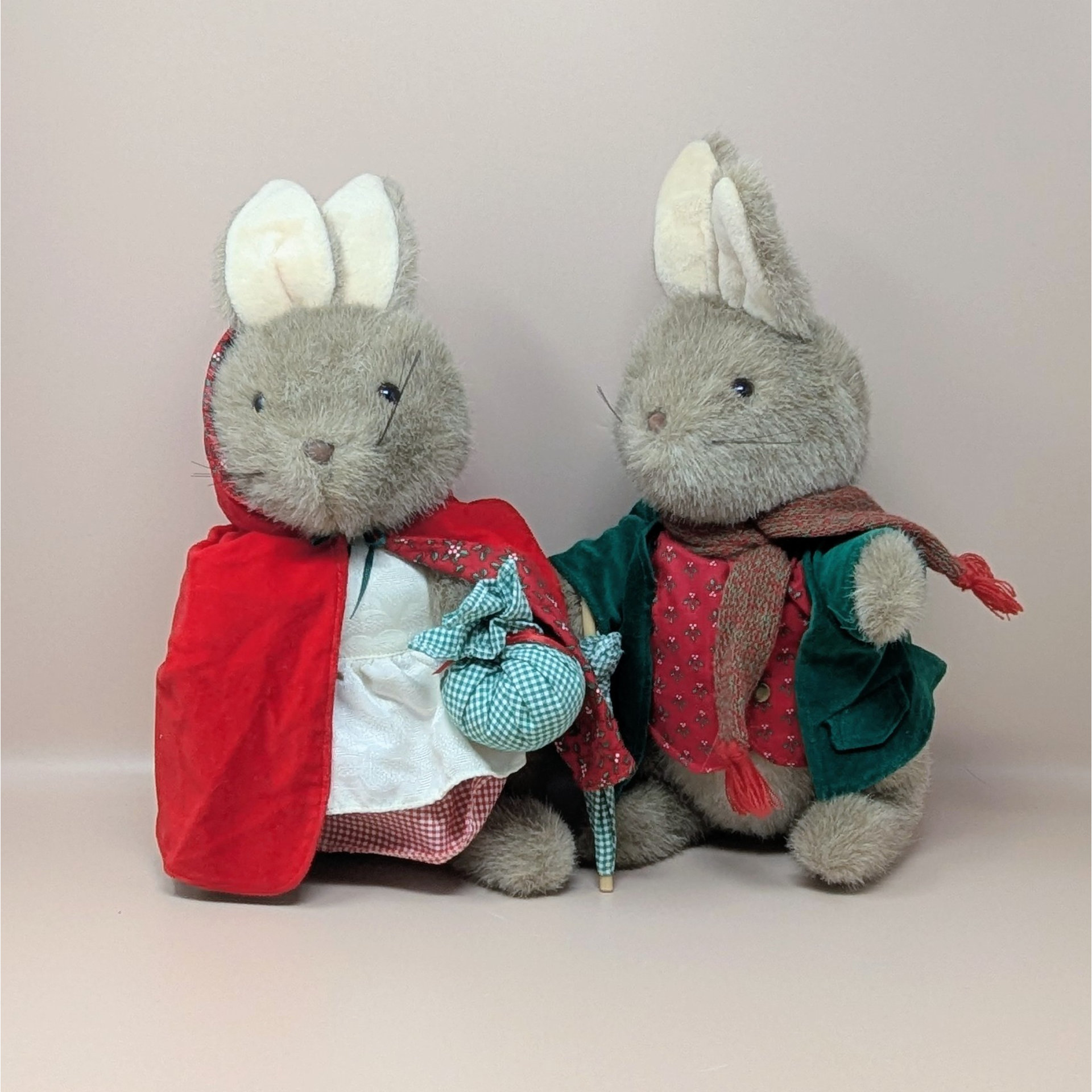 Two vintage Peter Rabbit and Mrs Rabbit plush bunnies wearing detailed outfits including a red hooded cape and a green velvet jacket