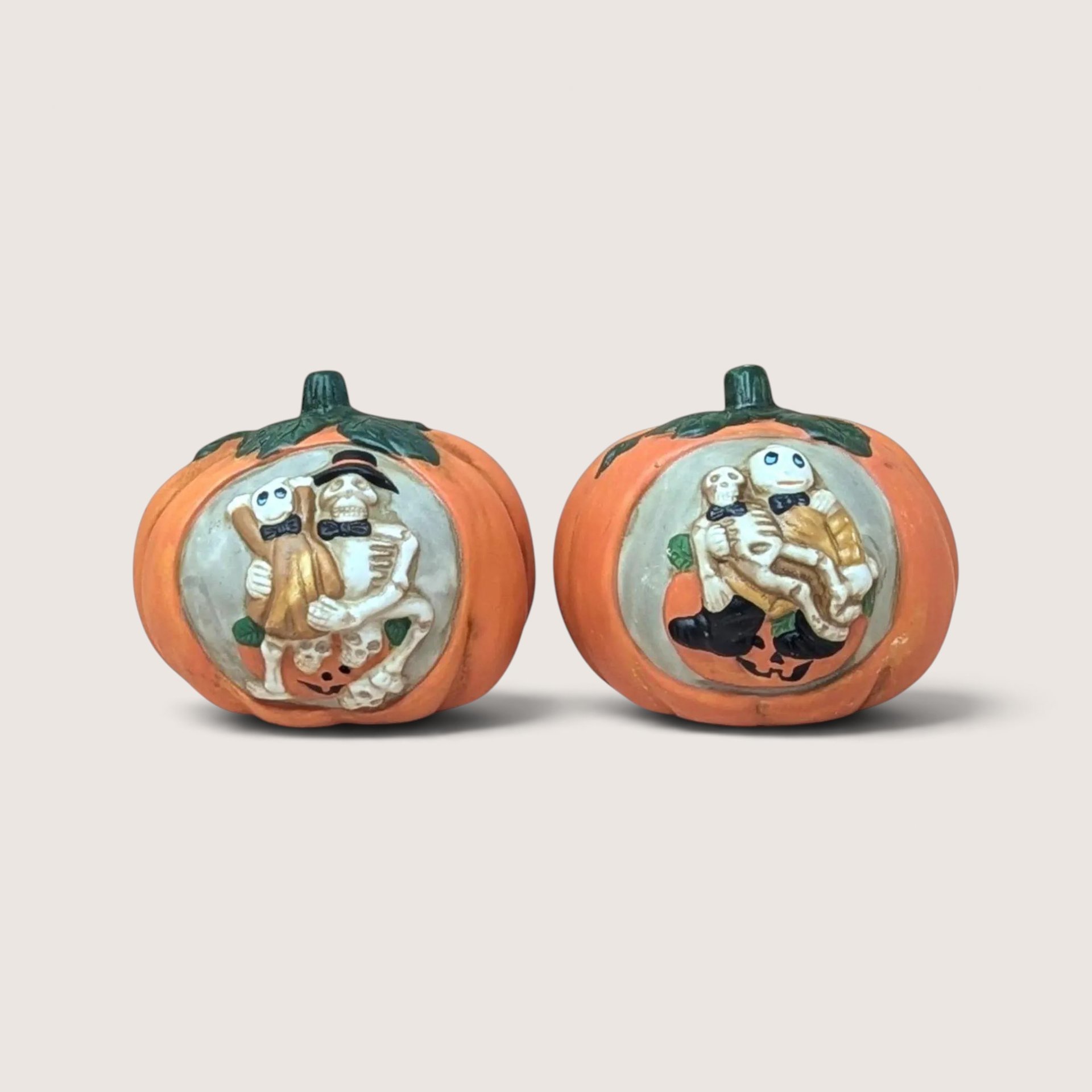 Two vintage ceramic pumpkin tealight candle holders featuring hand-painted relief panels of skeleton couples.