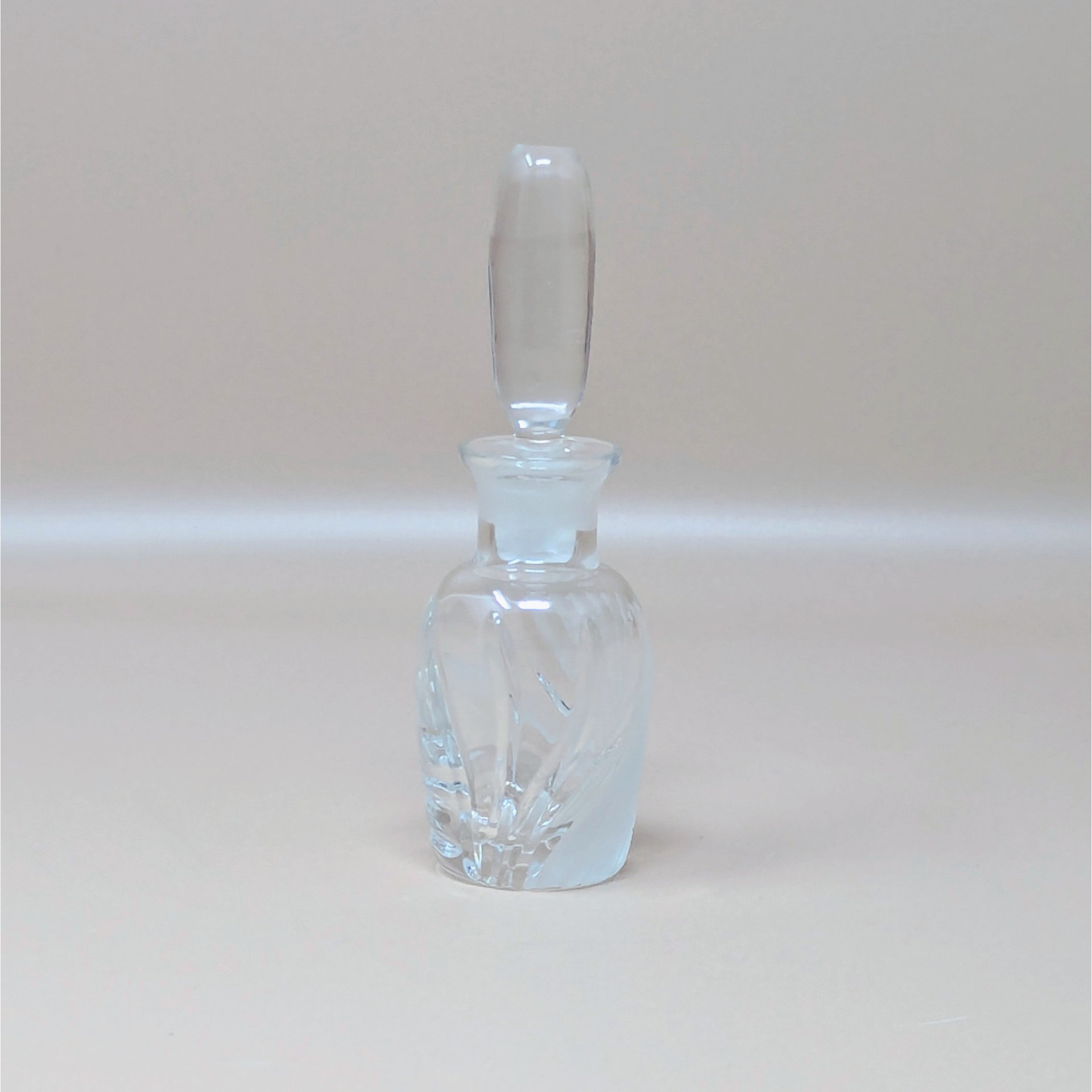 A vintage Lenox glass perfume bottle with the iconic Windswept frosted swirl pattern. The bottle features a tall, smooth clear stopper and is photographed against a neutral dune background.
