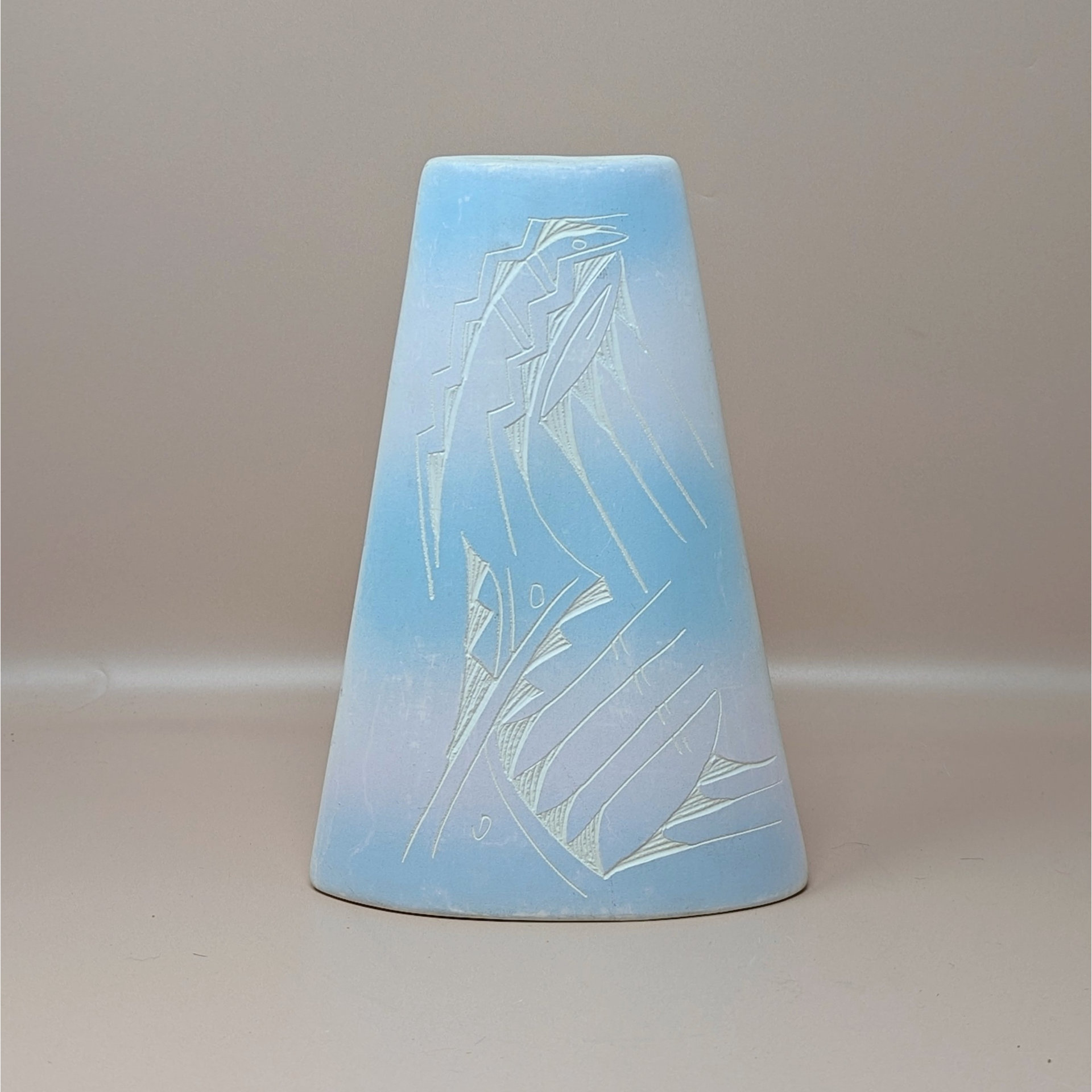 A conical studio pottery vase with a soft blue and pink ombre glaze. The front features an etched sgraffito design of stylized geometric and avian motifs, shown against a neutral background.