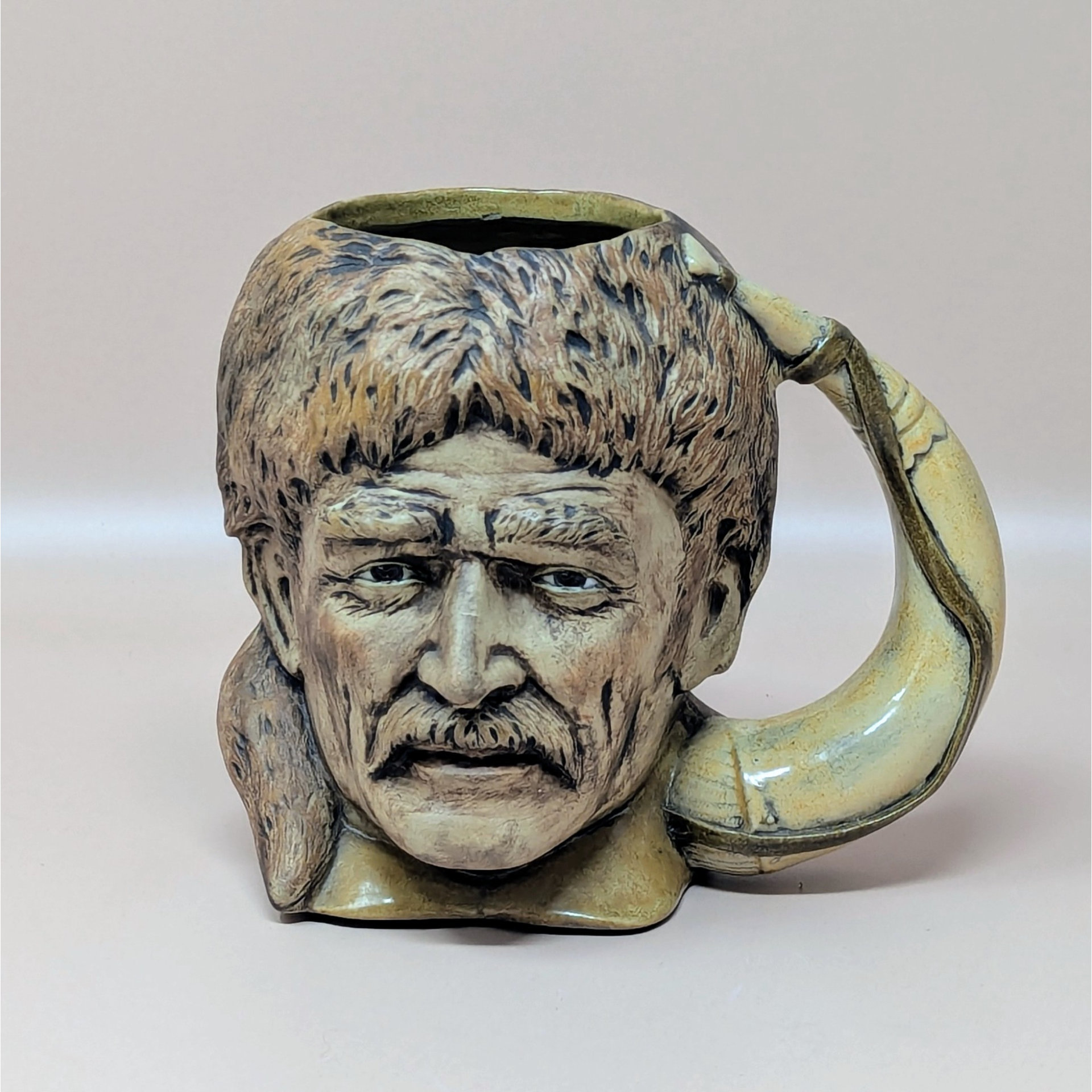 A vintage ceramic mug shaped like the head of Davy Crockett wearing a coonskin cap. The handle is shaped like a curved powder horn. The painting is detailed with realistic facial features and fur textures.