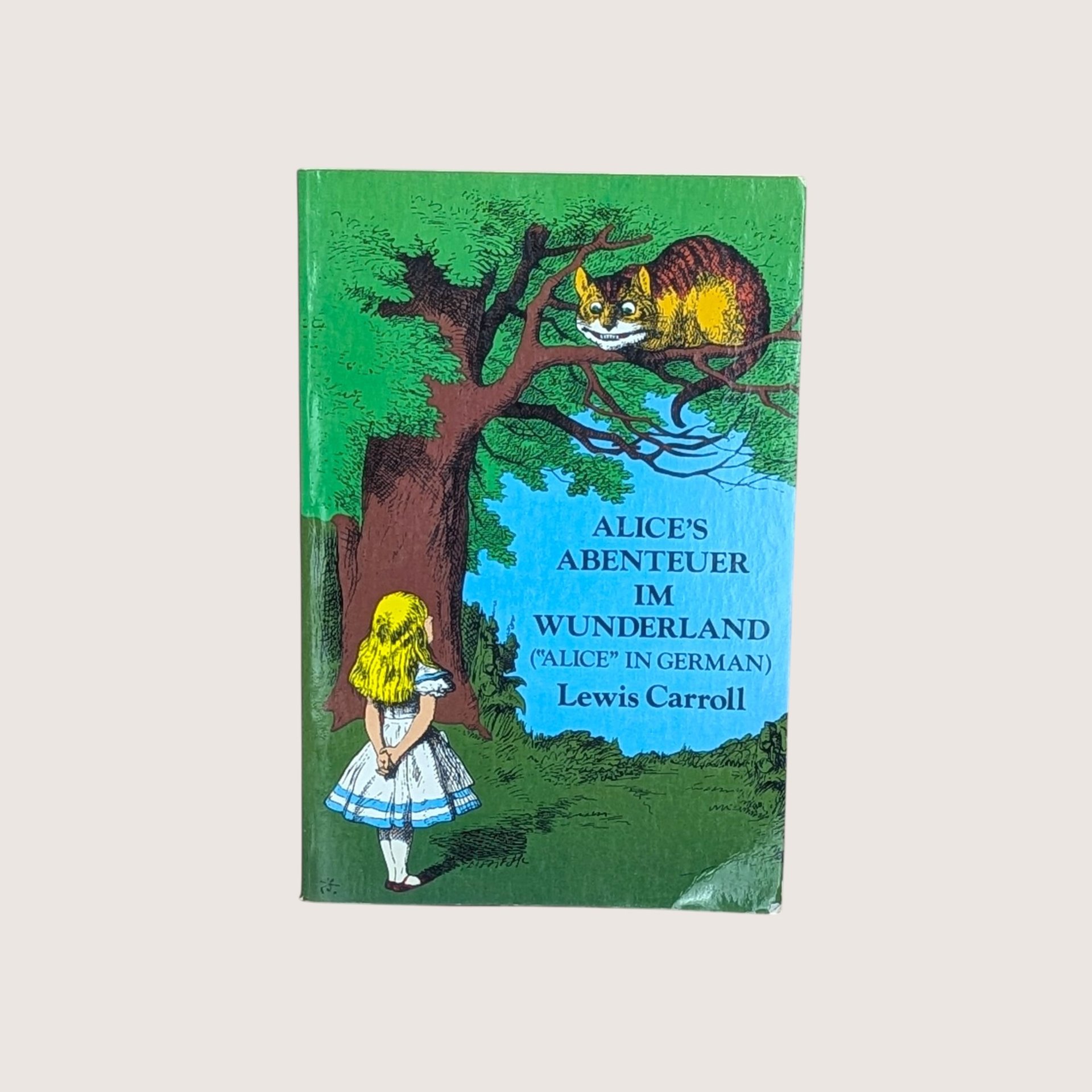 Step through the looking glass with this enchanting vintage 1974 edition of Lewis Carroll's timeless classic, translated into German. This softcover volume features a beautifully illustrated cover depicting the iconic encounter between Alice and the grinning Cheshire Cat.  Size: 8 inches by 5.25 inches (Measurements are close but approximate)  Decade: 1974  Style: Literary Whimsy  Condition: Good vintage condition with light wear to the cover and some visible glue residue on the inner spine before the title