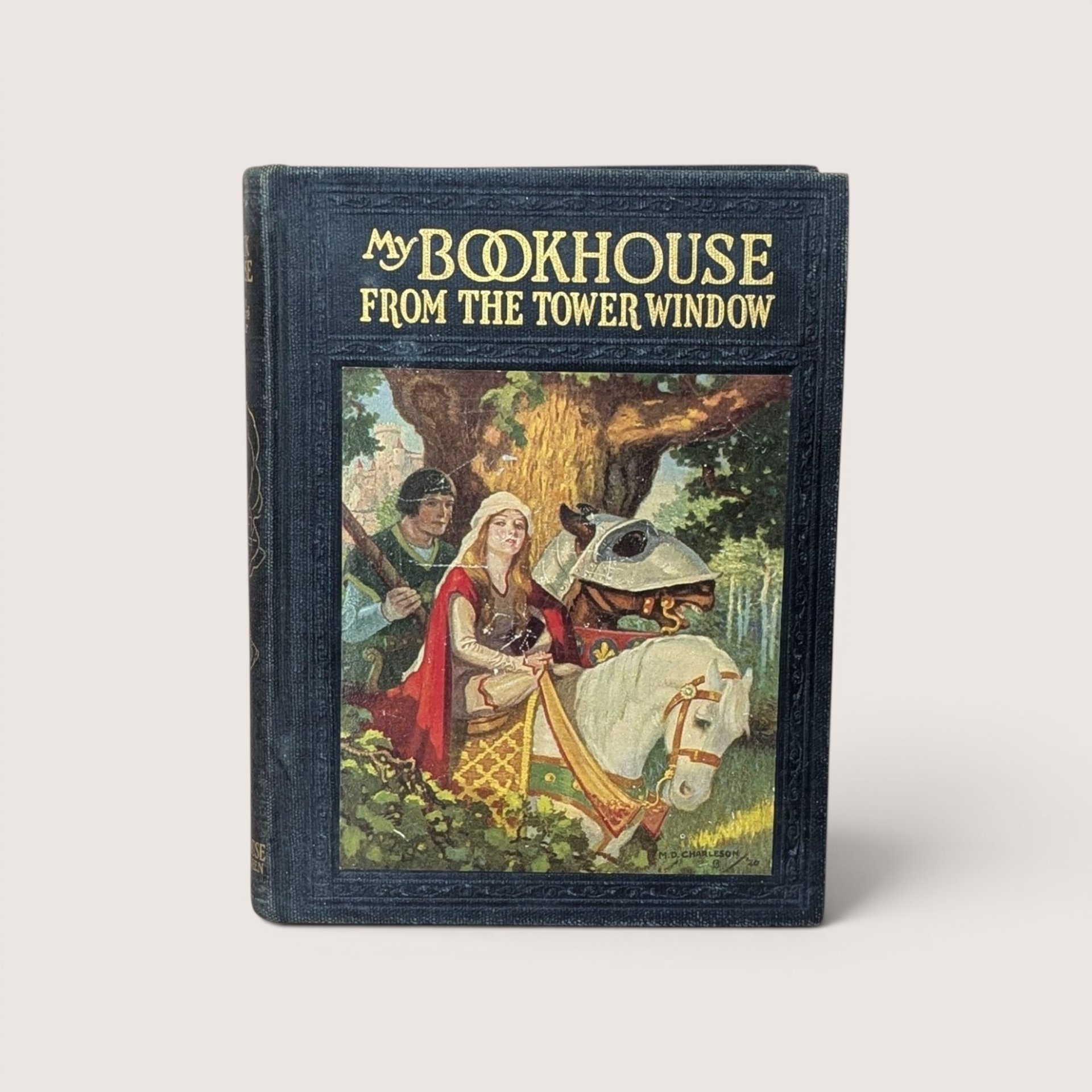 An antique black cloth hardcover book with gold text and a colorful illustration of a medieval knight and lady on horseback