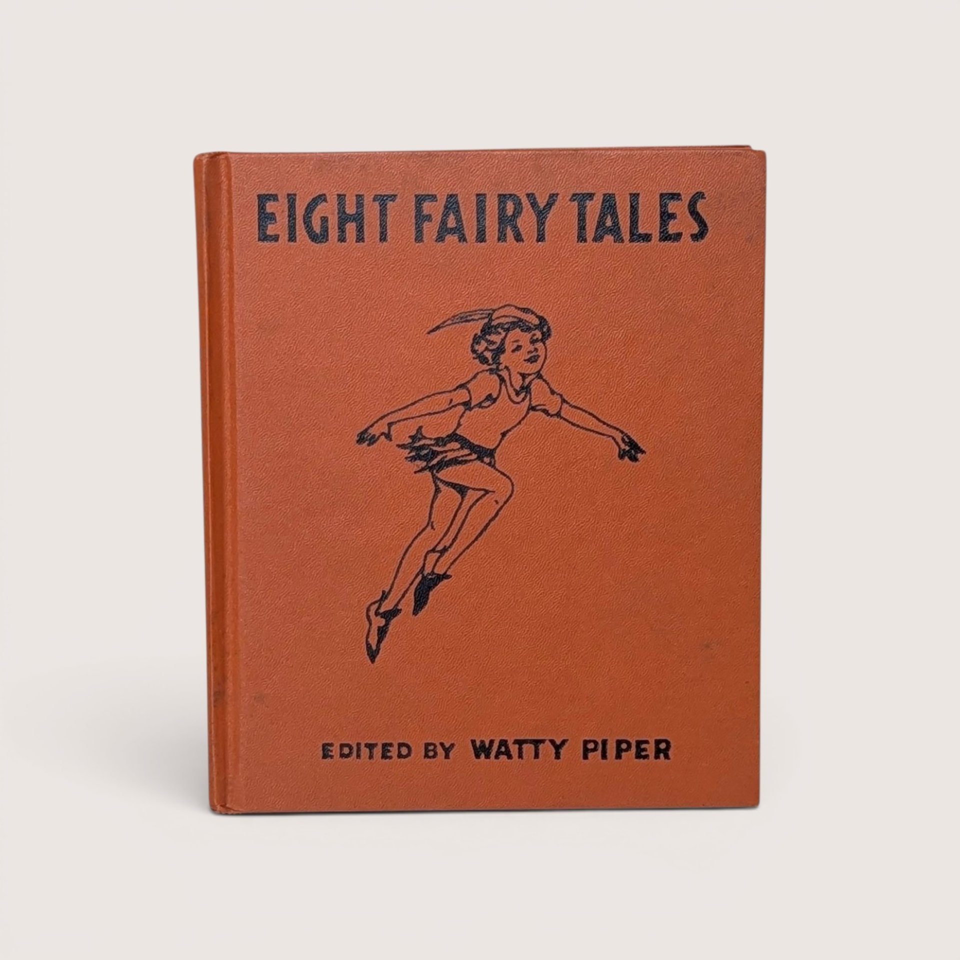 A vintage orange cloth hardcover book with a black illustration of Peter Pan leaping on the front cover
