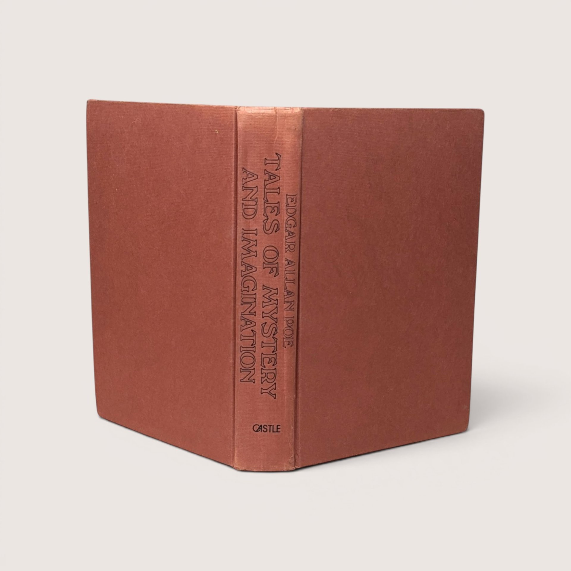 A vintage terracotta orange cloth hardcover book spine standing upright against a neutral backdrop