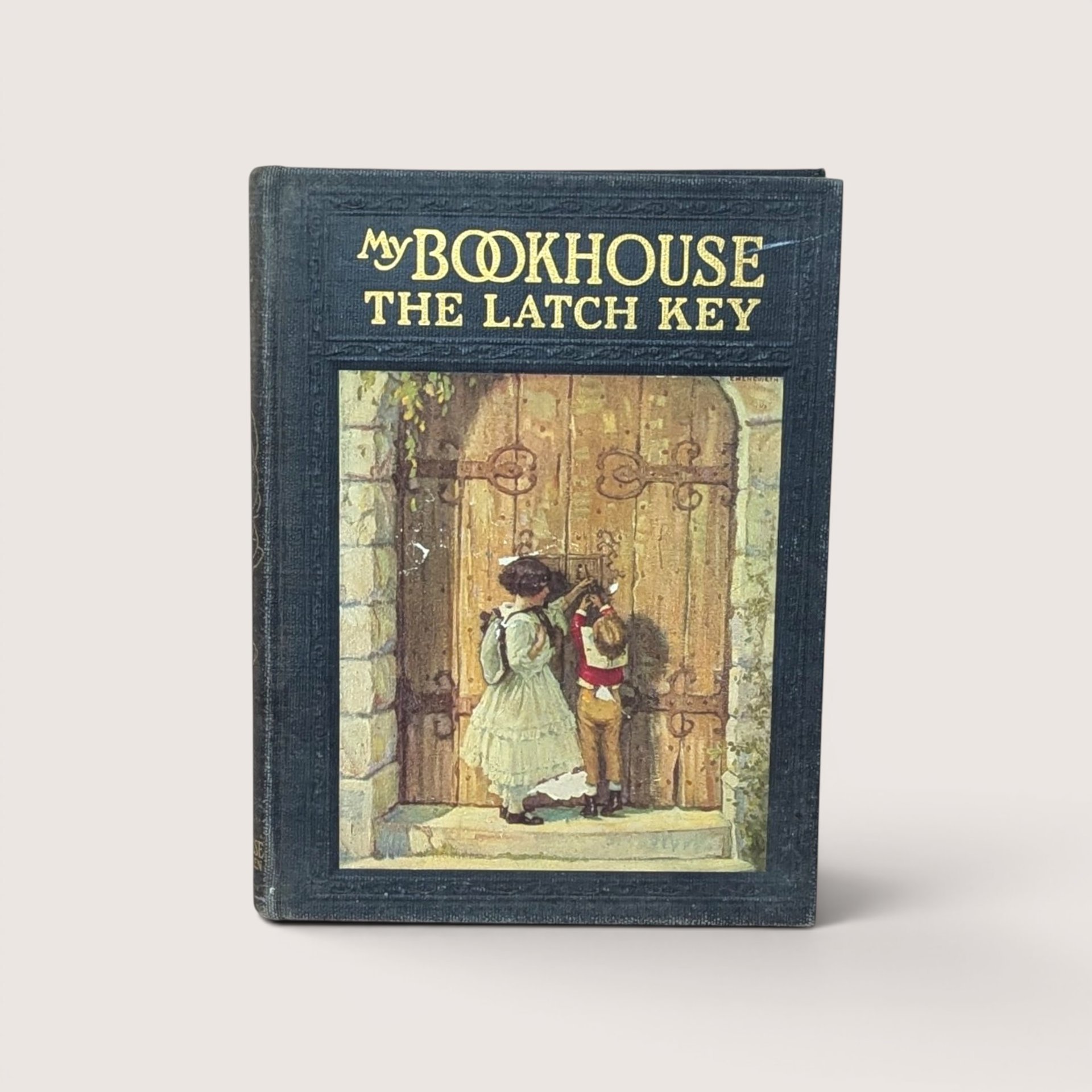 An antique black cloth hardcover book with gold text and a colorful illustration of two children at a large wooden door