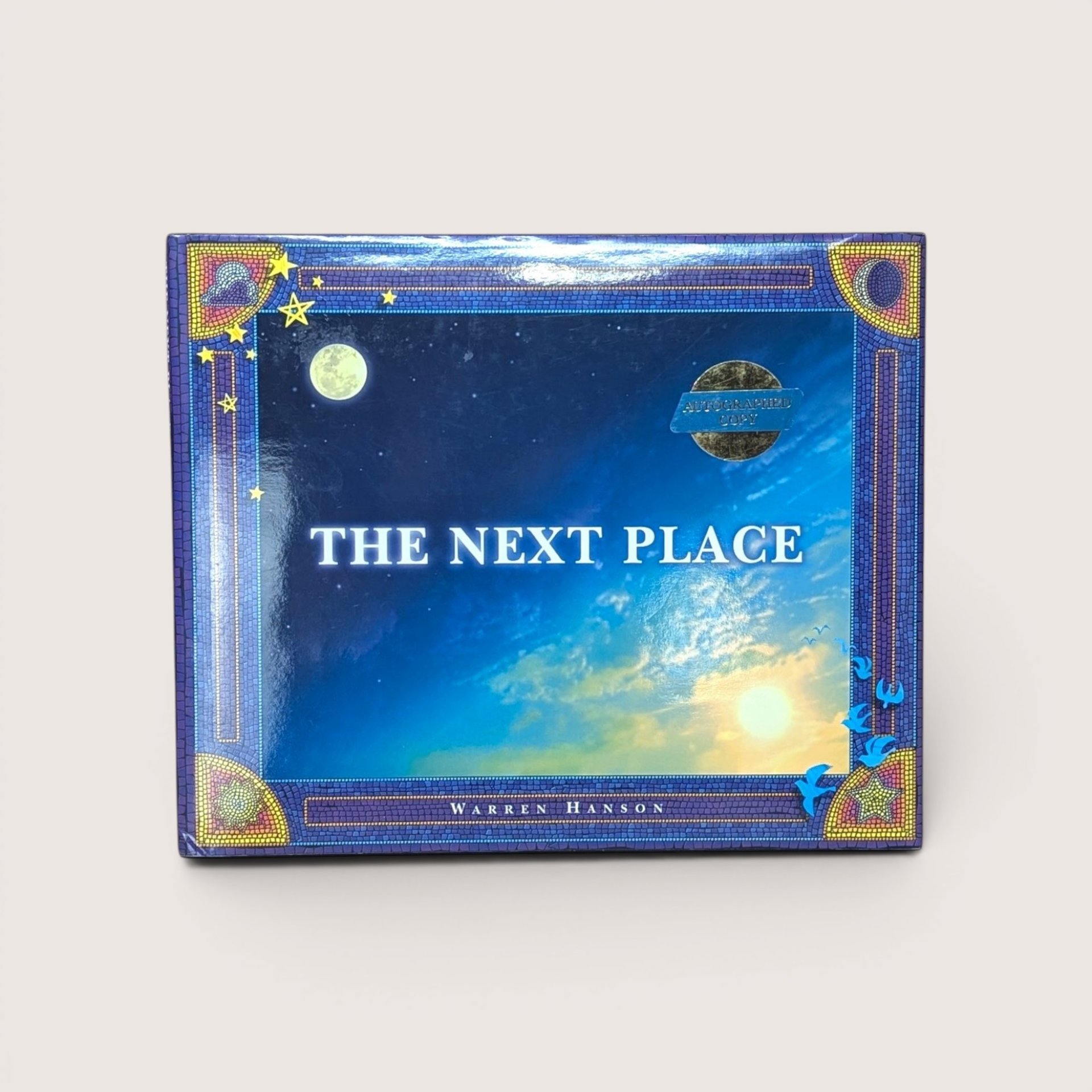 A vintage landscape hardcover book cover featuring a starry blue sky, full moon, and mosaic tile border